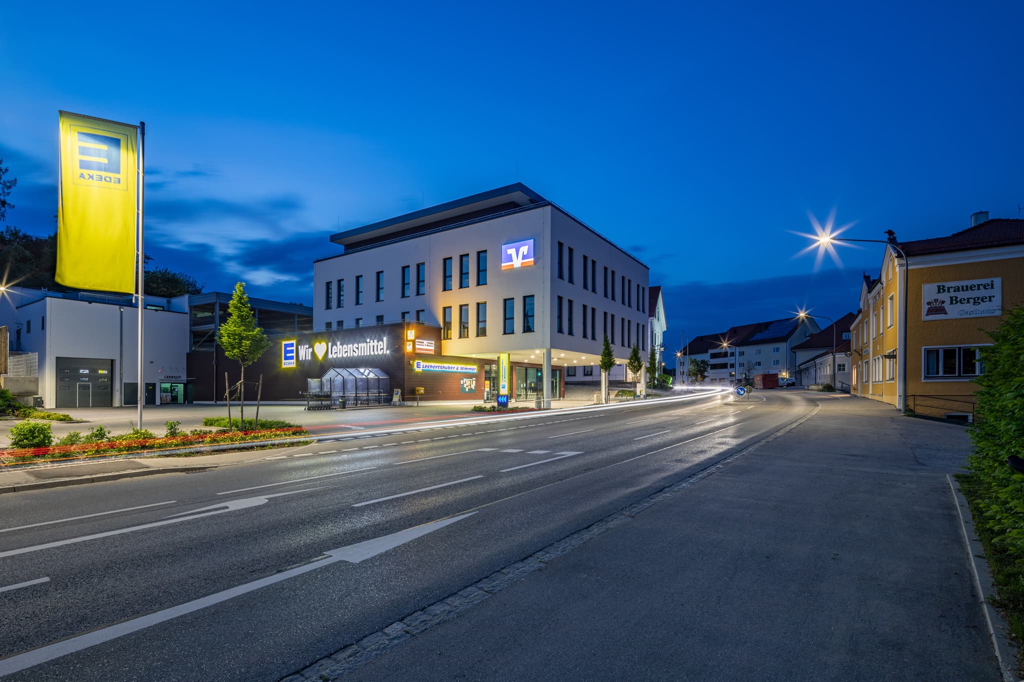 Nachtaufnahme eines Edeka- und Raiffeisenbank-Gebäudes in Reischach, Landkreis Altötting, Oberbayern, Region Inn-Salzach, Deutschland.
