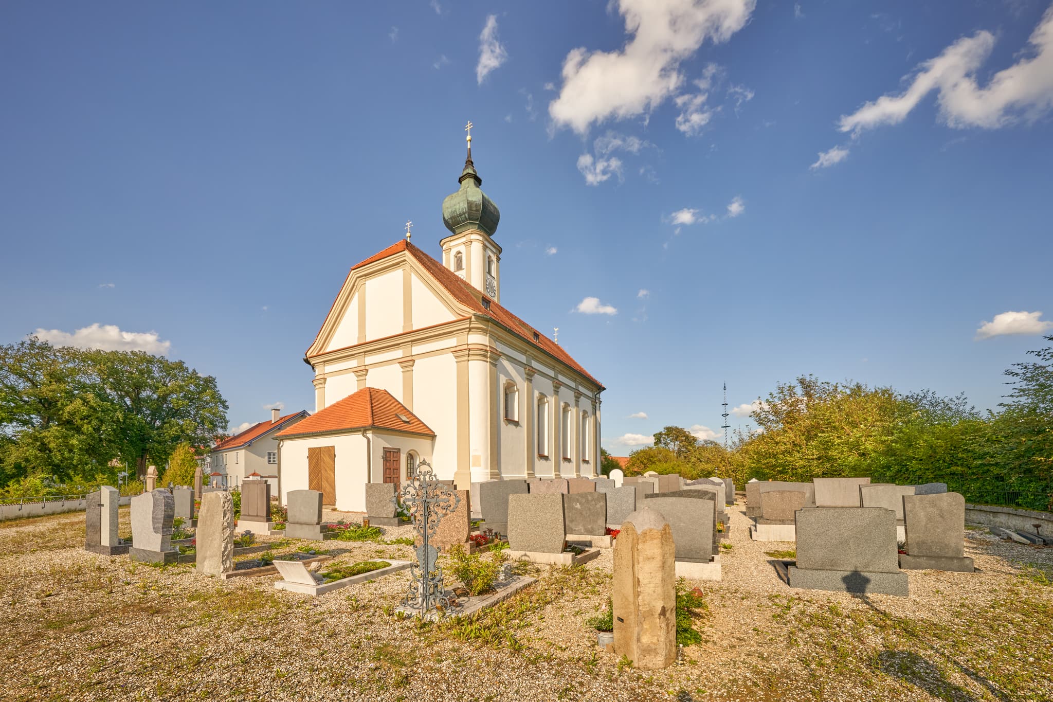 Kirche St. Martin, Niedertaufkirchen, Mühldorf am Inn, Oberbayern. Gotteshaus mit Friedhof unter blauem Himmel.