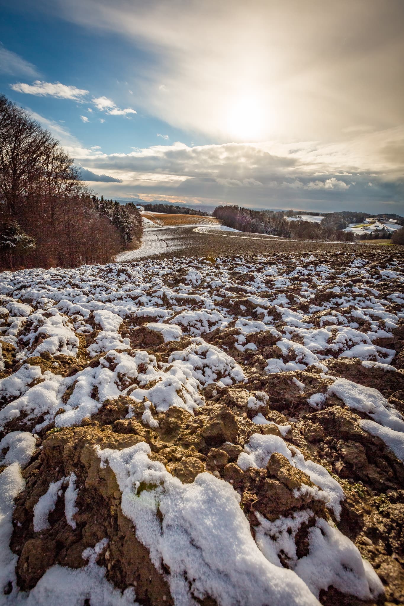 Verschneite Ackerlandschaft mit Feldern und Wäldern von der Friesing Aussicht bei Reischach im Landkreis Altötting, Oberbayern, Inn-Salzach, Deutschland.