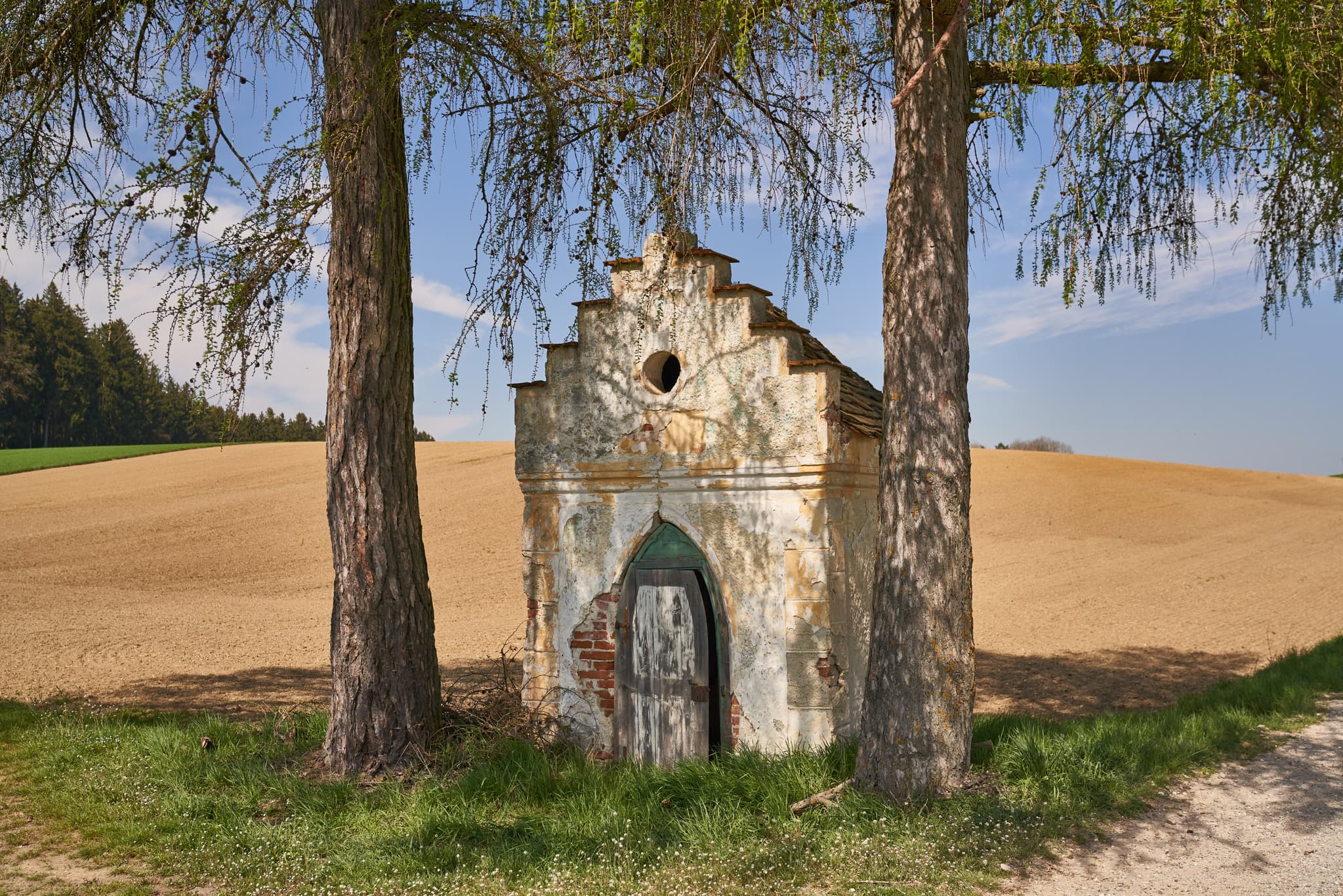 Bildstock zwischen Kirchisen und Kainrading mit Feldern und Wald bei Mettenheim im Landkreis Mühldorf am Inn, Oberbayern.