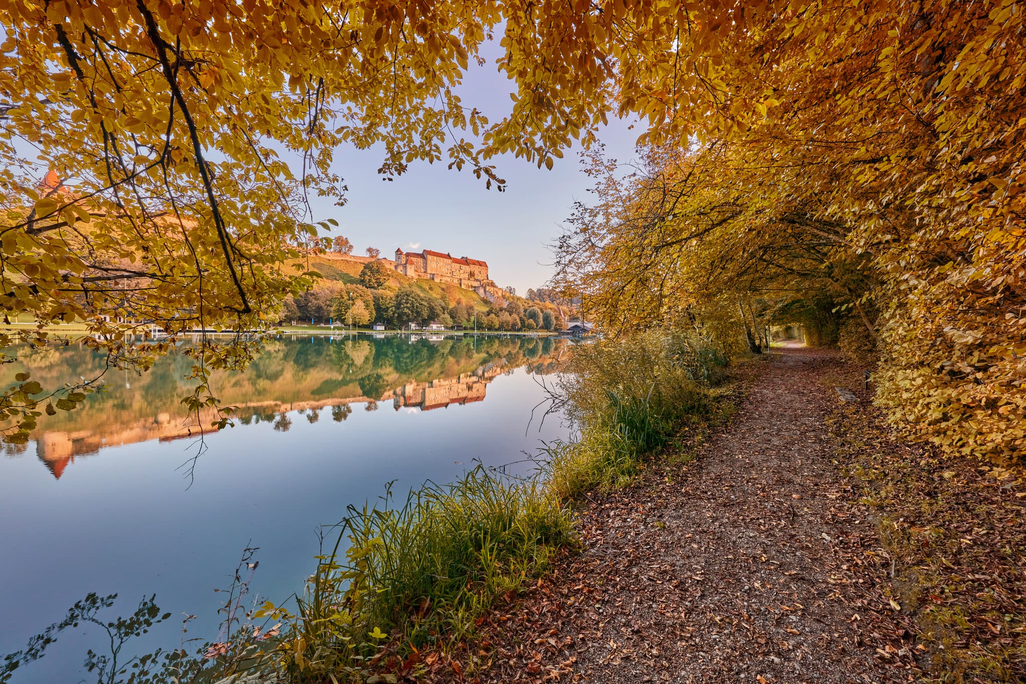 Herbstliche Landschaft am Wöhrsee in Burghausen, Altötting, Oberbayern. See mit Laubengang und Burgsilhouette im Hintergrund, gelegen in der Inn-Salzach Region.