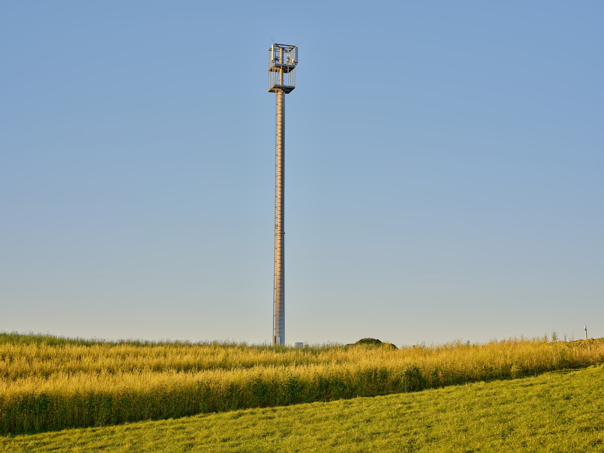 Sendemast in Weingarten, Reischach, Landkreis Altötting, Oberbayern. Weite Felder und klarer Himmel charakterisieren die Szenerie.