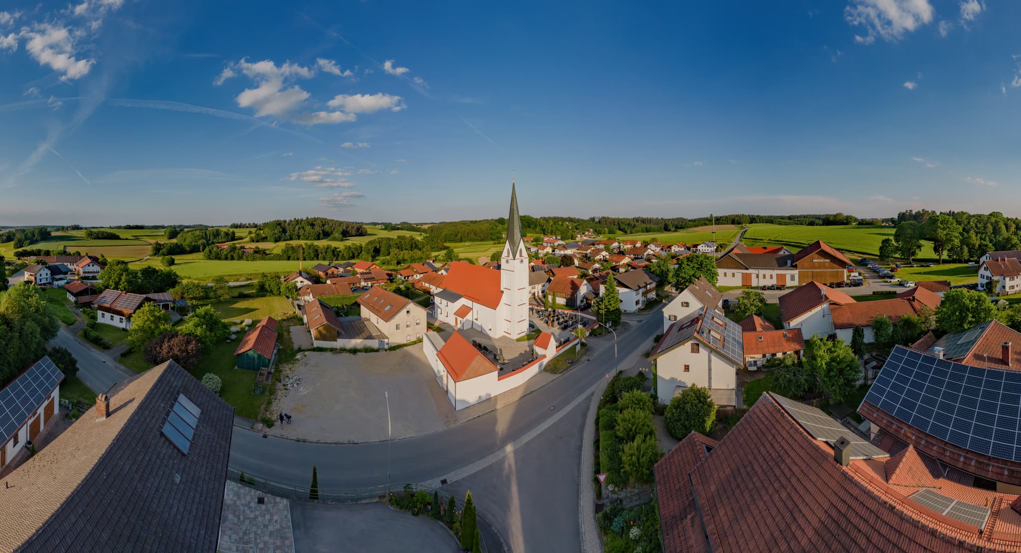 Panorama Ortsansicht von Arbing, Ortsteil von Reischach, mit der Pfarrkirche St. Georg. Eingebettet in die Landschaft des Holzlandes im Landkreis Altötting.
