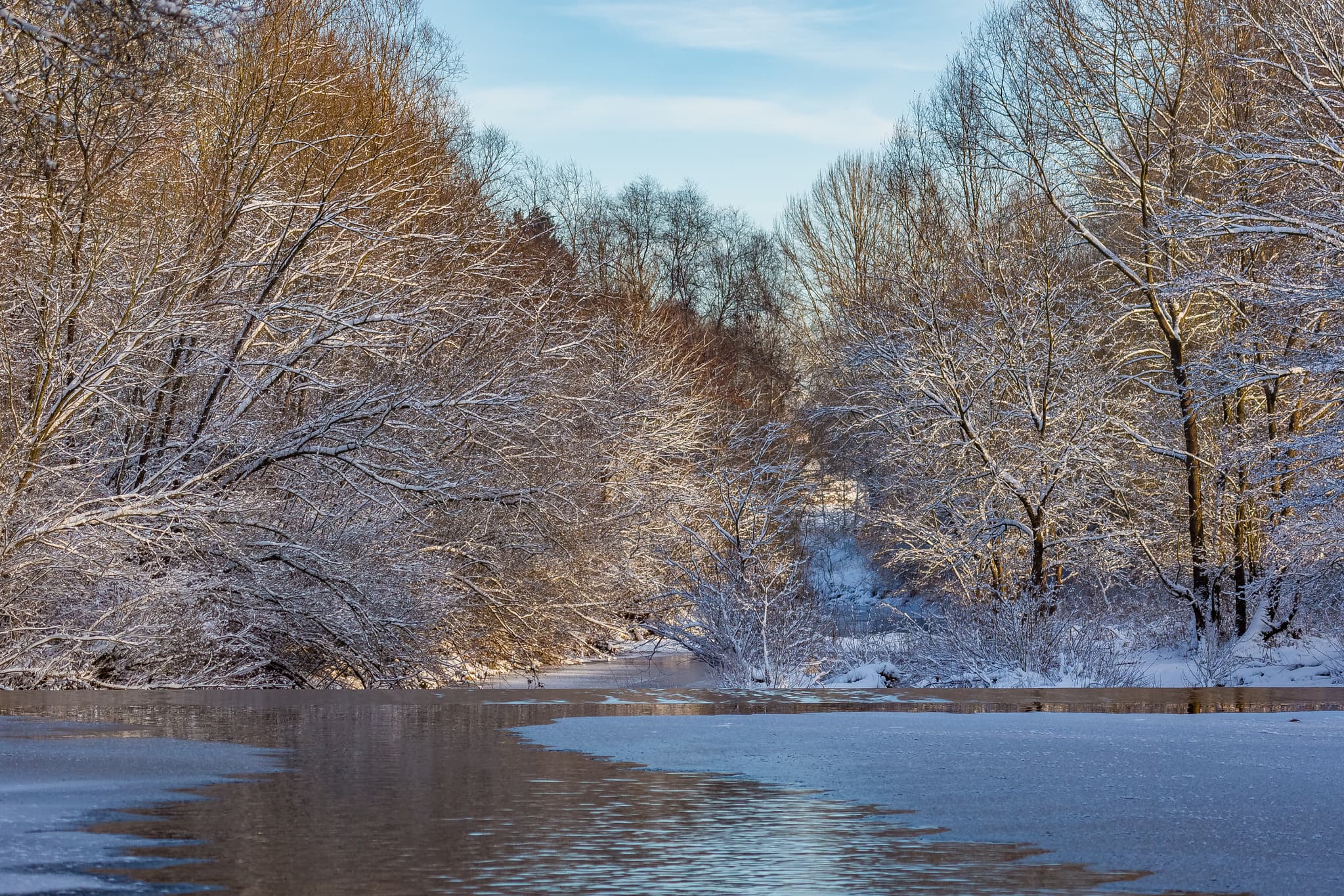Winterliche Isen in Winhöring, Landkreis Altötting, Oberbayern, Deutschland. Die verschneite Landschaft zeigt gefrorene Gewässer und schneebedeckte Bäume.