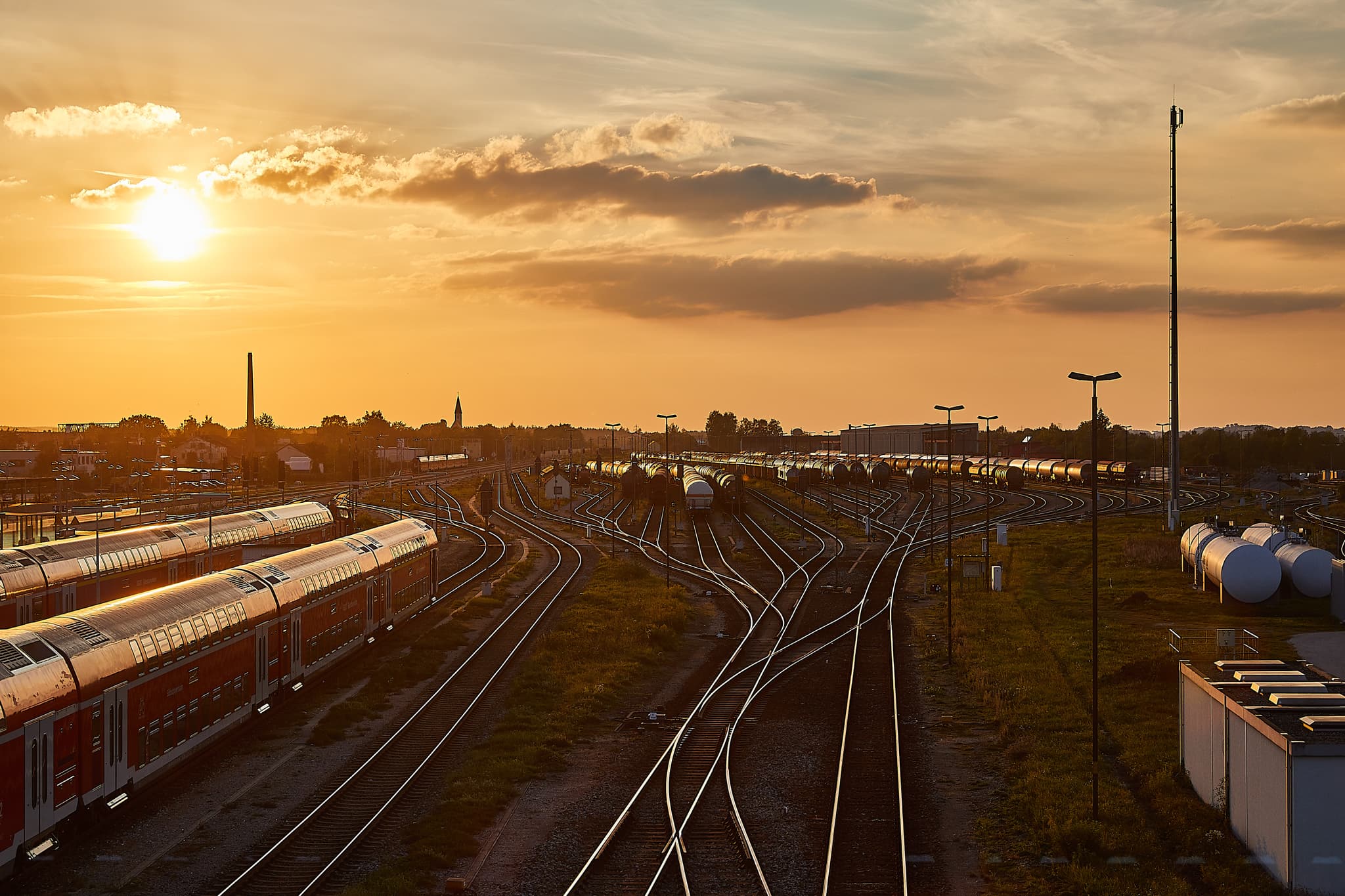 Bahnhof Mühldorf am Inn, Oberbayern. Gleisanlagen, Züge, Tanks im Sonnenuntergang. Industrielandschaft der Inn-Salzach Region im Landkreis Mühldorf am Inn.