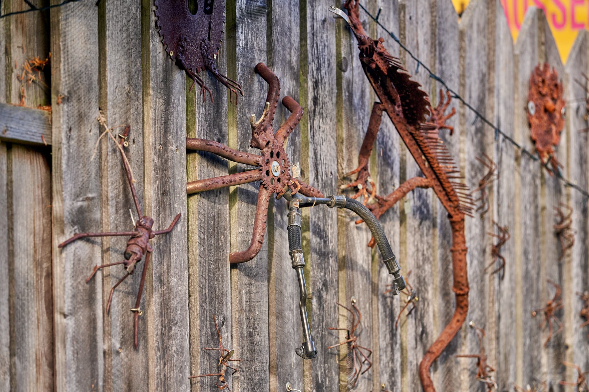 Detailaufnahme eines Zauns mit rostigen Metallskulpturen am Hörniweg in Schönau, Rottal-Inn, Niederbayern, Holzland, Deutschland.