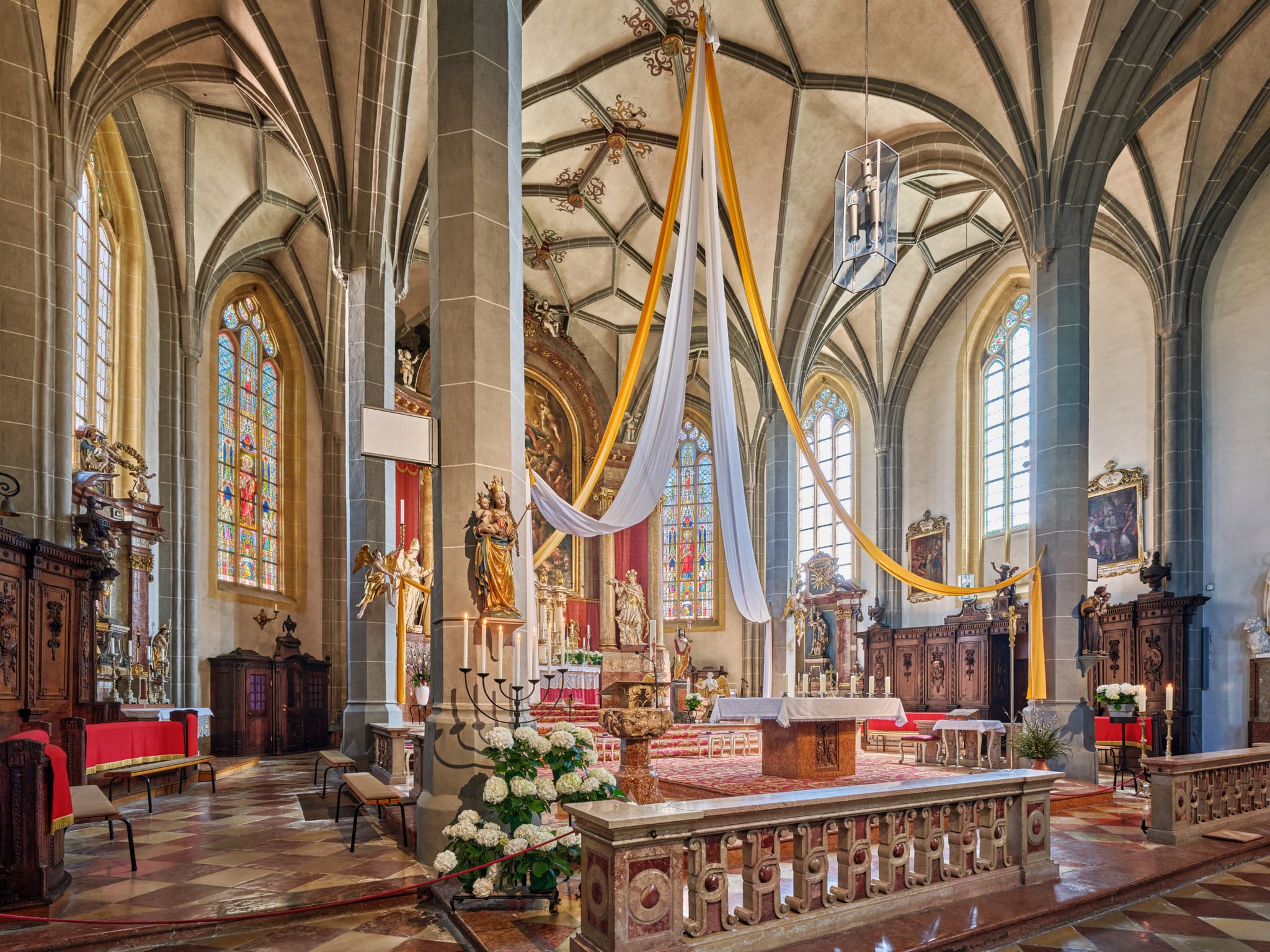 Innenansicht der Stiftskirche am Kapellplatz Altötting, Oberbayern. Hohe Gewölbe, bunte Buntglasfenster und ein prachtvoller Altar.