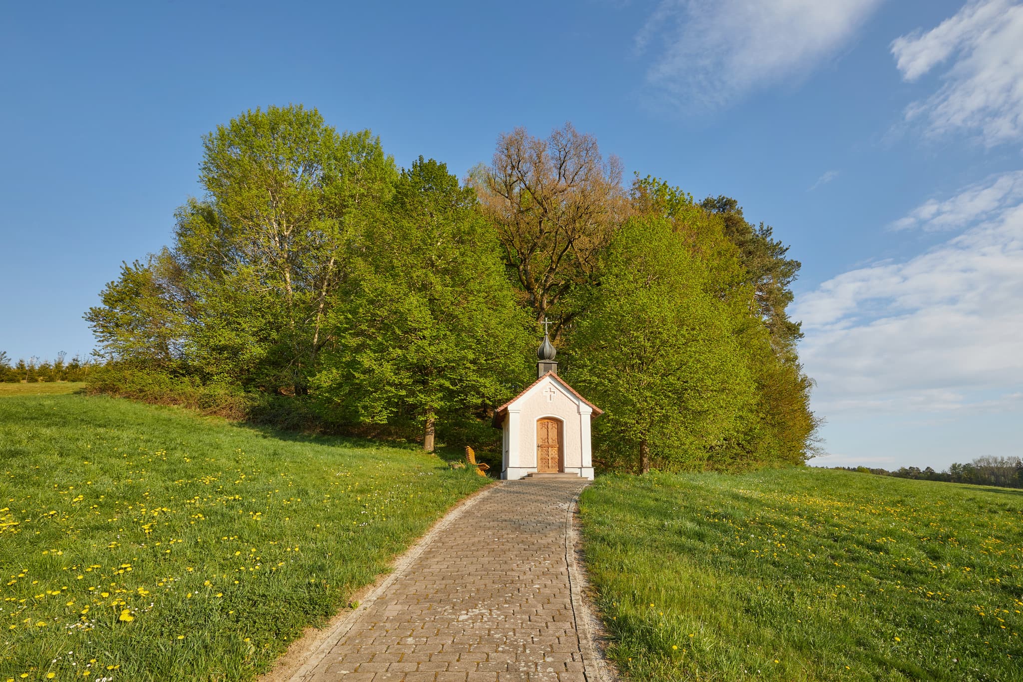 Hickerstall Kapelle in Wurmannsquick, Rottal-Inn, Niederbayern. Eine kleine Kapelle auf einer grünen Anhöhe, umgeben von Wiesen und Bäumen im Holzland.