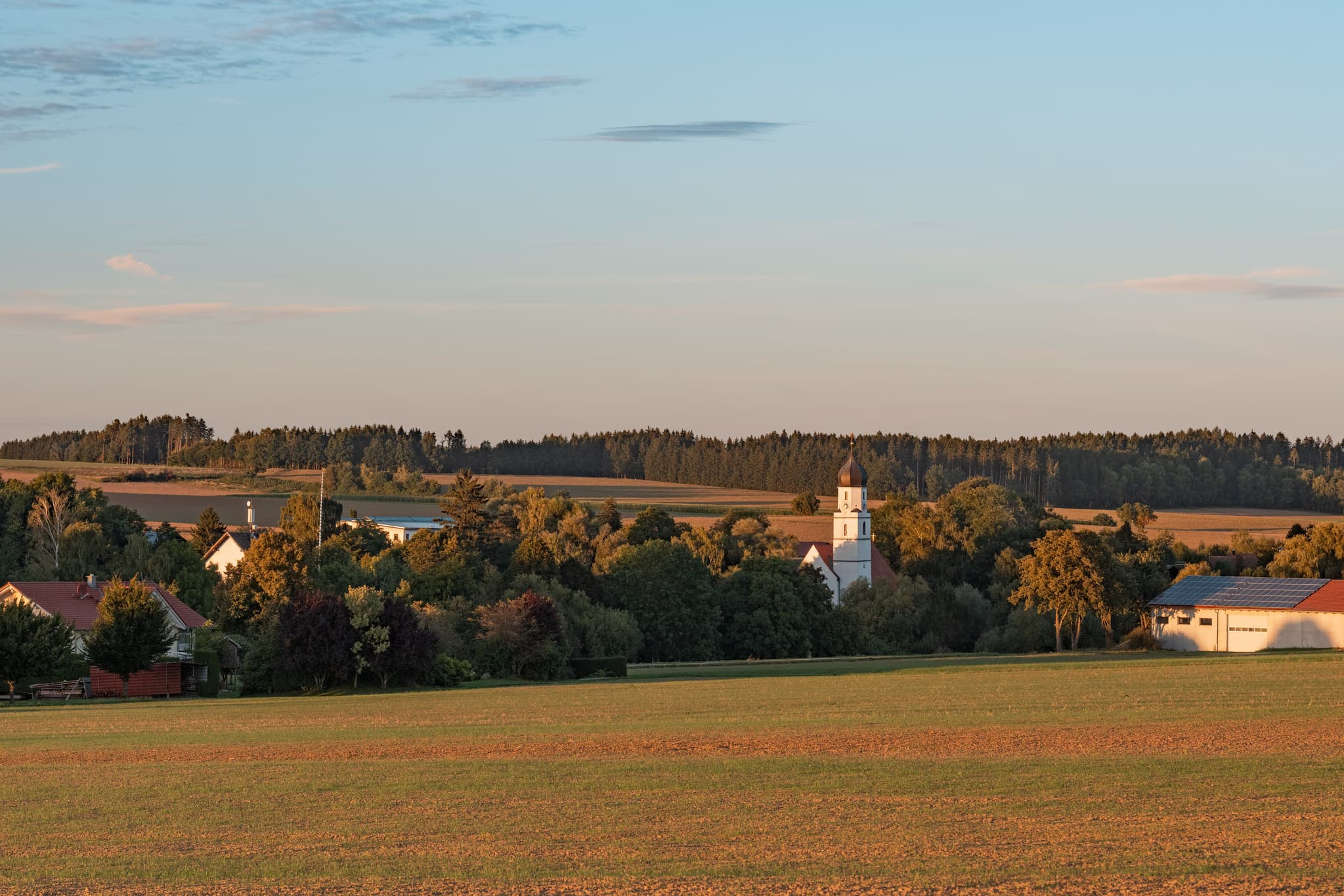 Ortsansicht von Dirnaich mit Kirche St. Martin, Rottal-Inn, Niederbayern. Ländliche Idylle umgeben von Wiesen, Feldern und Waldin der  Region Holzland.