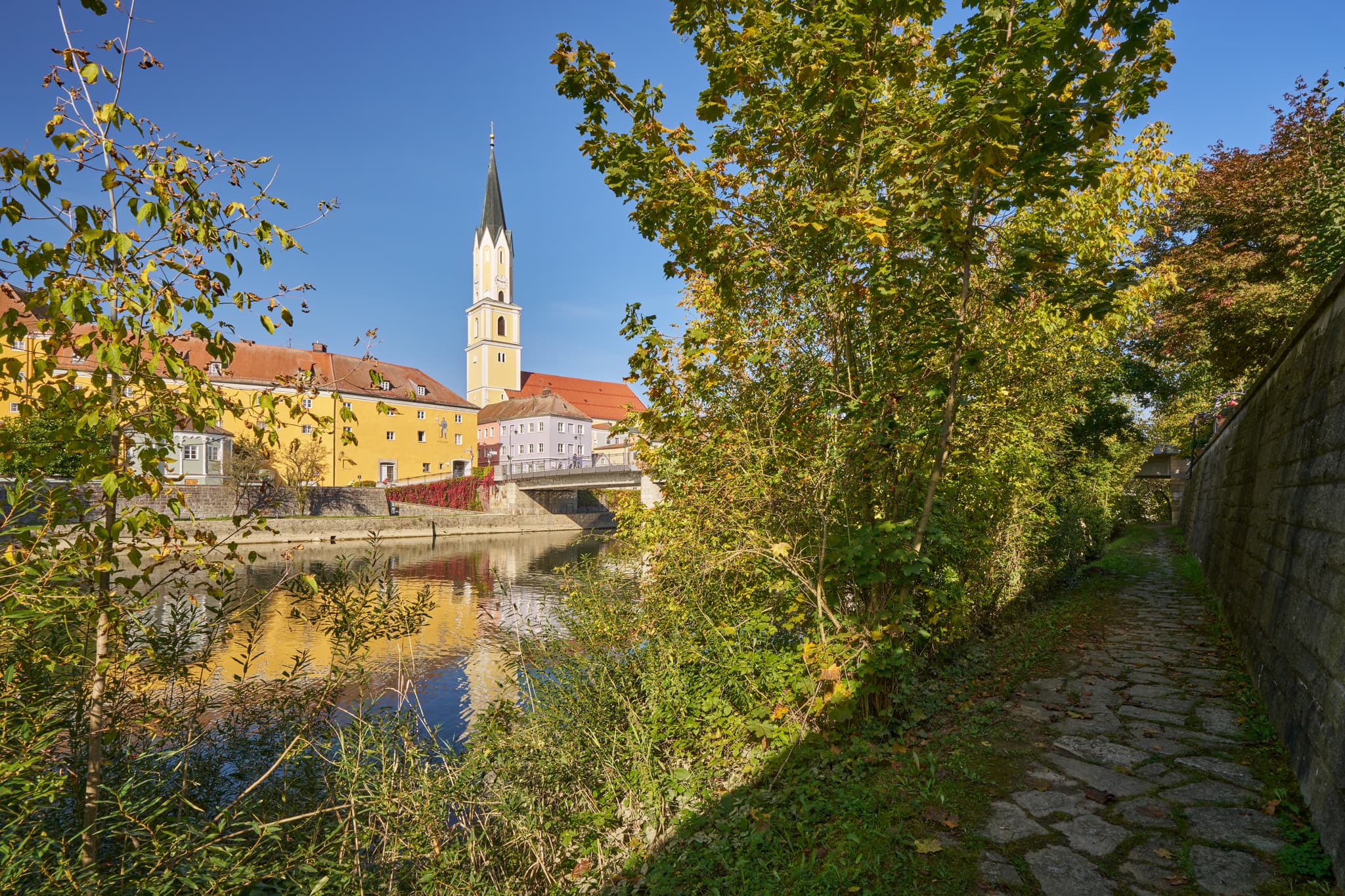 Stadtansicht Vilshofen an der Vils, Landkreis Passau, Niederbayern. Historische Gebäude, Kirchturm und Brücke spiegeln sich im Fluss. Donau-Wald, Deutschland.