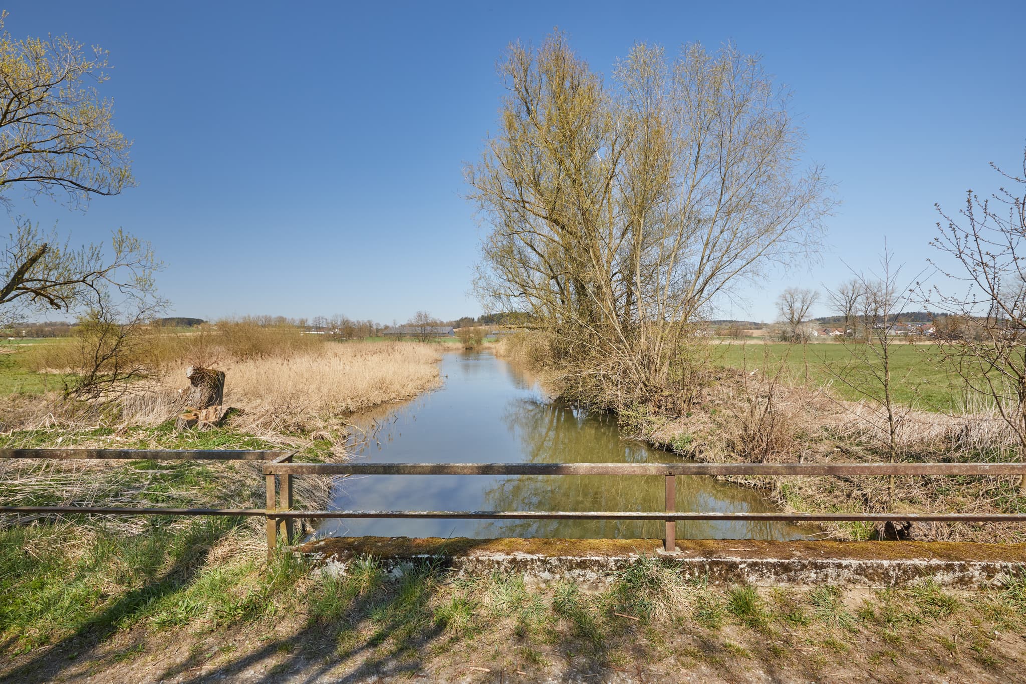 Rott Seitenarm in Unterdietfurt, Rottal-Inn, Niederbayern. Landschaft im Holzland, Deutschland, mit klarem Wasser, Wiesen und Bäumen unter blauem Himmel.