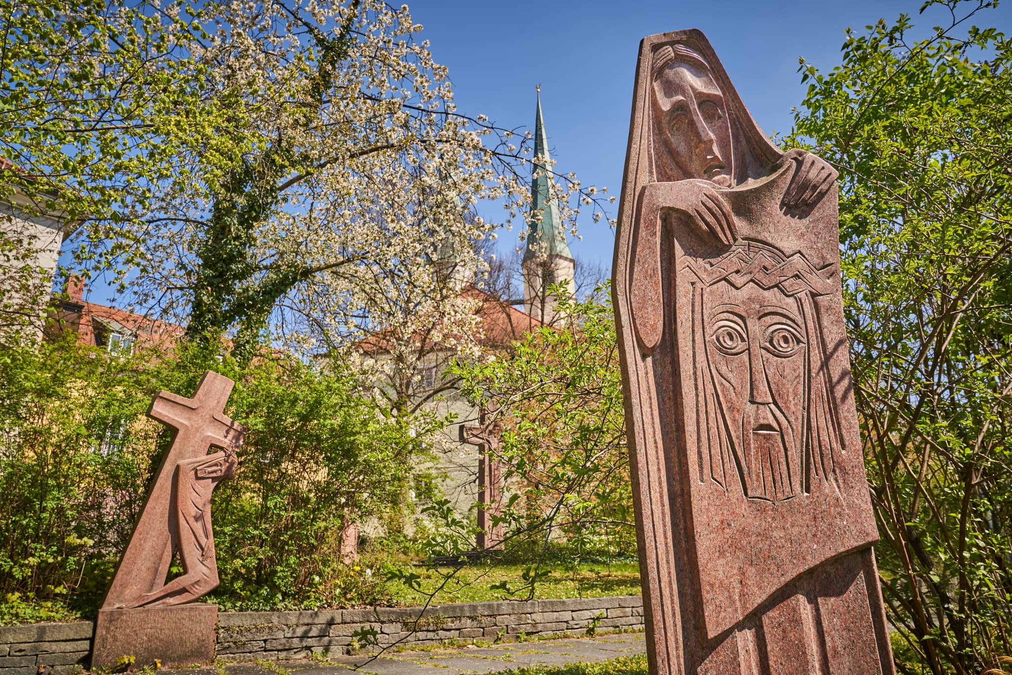 Kreuzwegdarstellung in Altötting, Landkreis Altötting, Oberbayern, Inn-Salzach, Deutschland. Skulpturen im Freien, umgeben von blühenden Bäumen und Grünflächen.