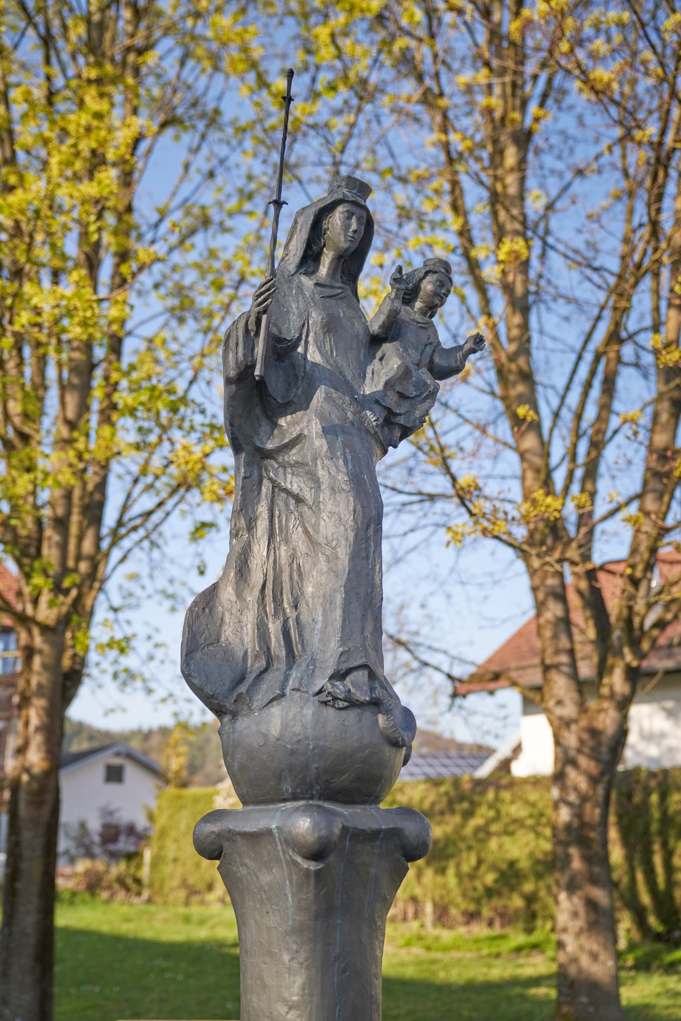 Statue Mariä Himmelfahrt in Perach, Landkreis Altötting, Oberbayern. Motiv im Inn-Salzach, Deutschland, zeigt die Skulptur vor frühlingshafter Natur.
