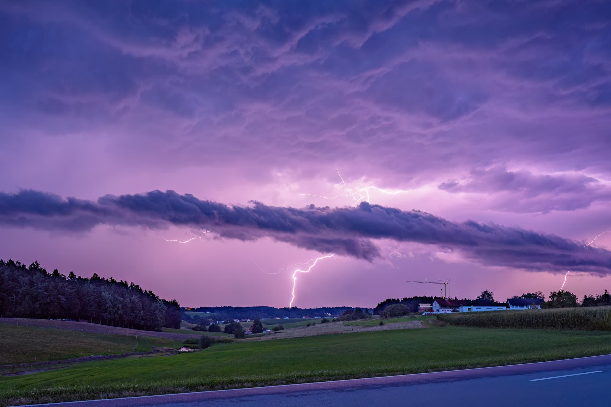 Gewitter mit Blitzen erhellt die weite Landschaft bei Golderberg, Reischach im Landkreis Altötting, Oberbayern, Region Inn-Salzach, Deutschland.