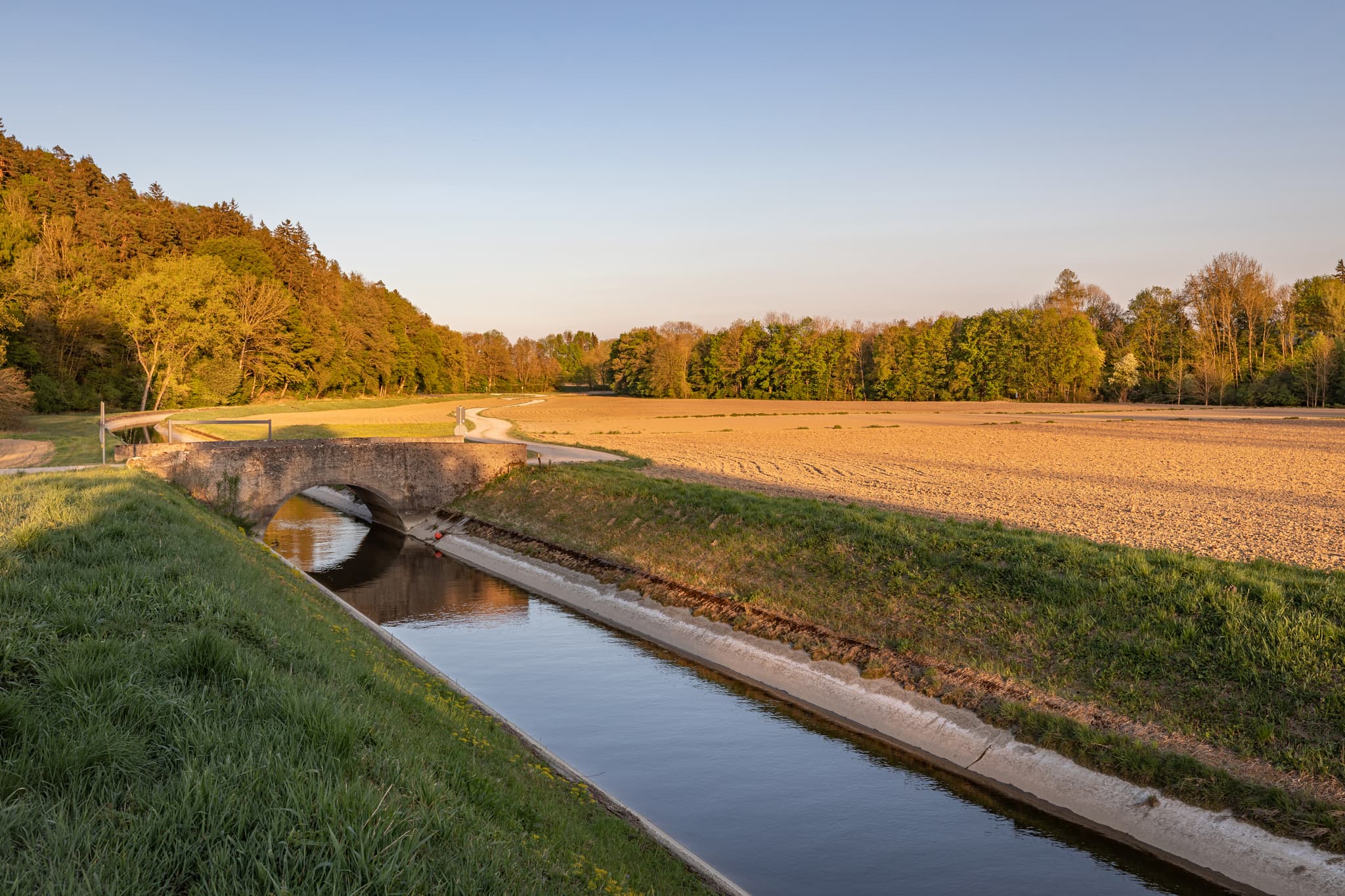 Isenkanal in Aufham, Winhöring, Altötting, Oberbayern. Die ländliche Natur der Region Inn-Salzach in Deutschland mit Kanal, Brücke, Feldern und Wald.