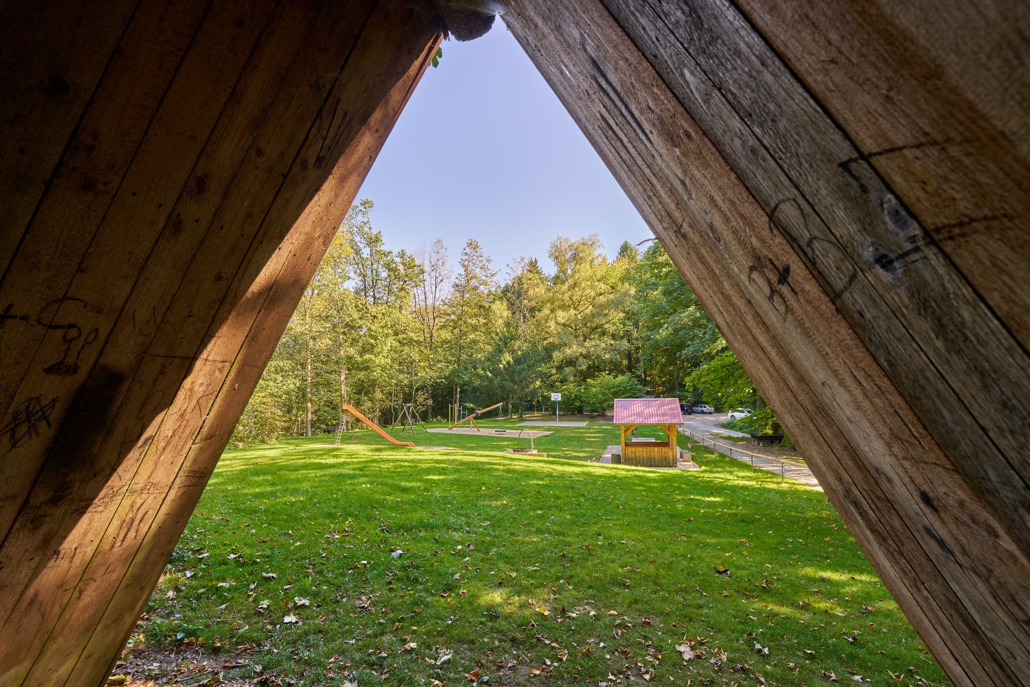 Spielplatz in Bad Griesbach, Passau, Niederbayern. Blick durch Holzkonstruktion auf Grünfläche mit Spielgeräten. Niederbayern, Bayern, Deutschland.