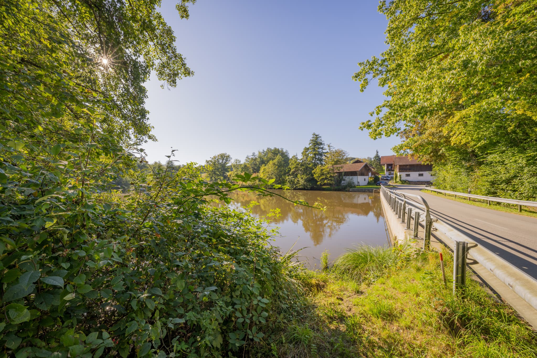 Weiher am Peterskirchener Bach bei Baumgarten mit Brücke. Landschaft nahe Dietersburg im Holzland, Rottal-Inn, Niederbayern, Deutschland.