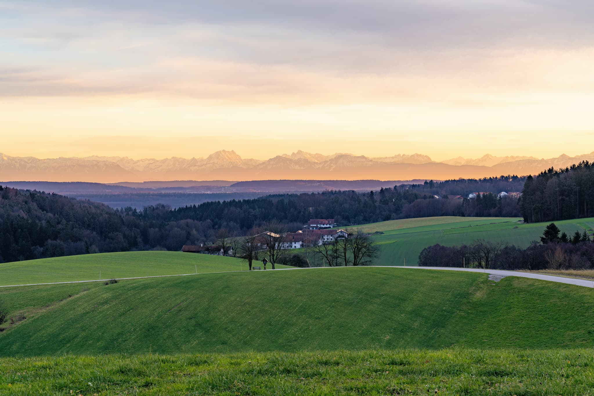 Blick aus Haizing, Erlbach, Altötting, Oberbayern. Die ländliche Inn-Salzach-Landschaft mit Gehöften, Feldern und Hügeln erstreckt sich vor Alpenkulisse.