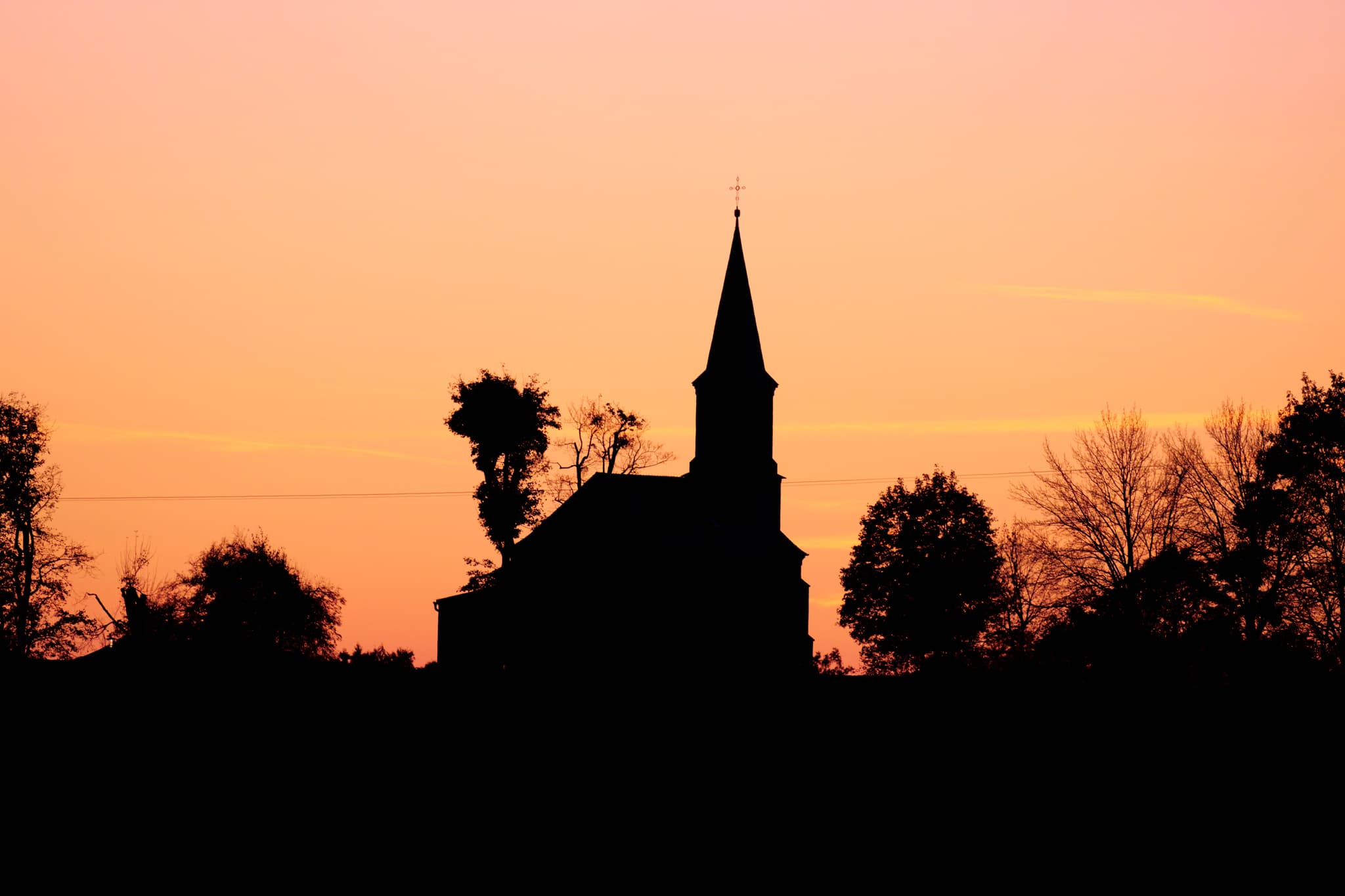 Silhouettenhafte Kirche in Wald bei Winhöring, Pleiskirchen, Kreis Altötting, Oberbayern. Die Abendlandschaft im Inn-Salzach-Gebiet in Deutschland.