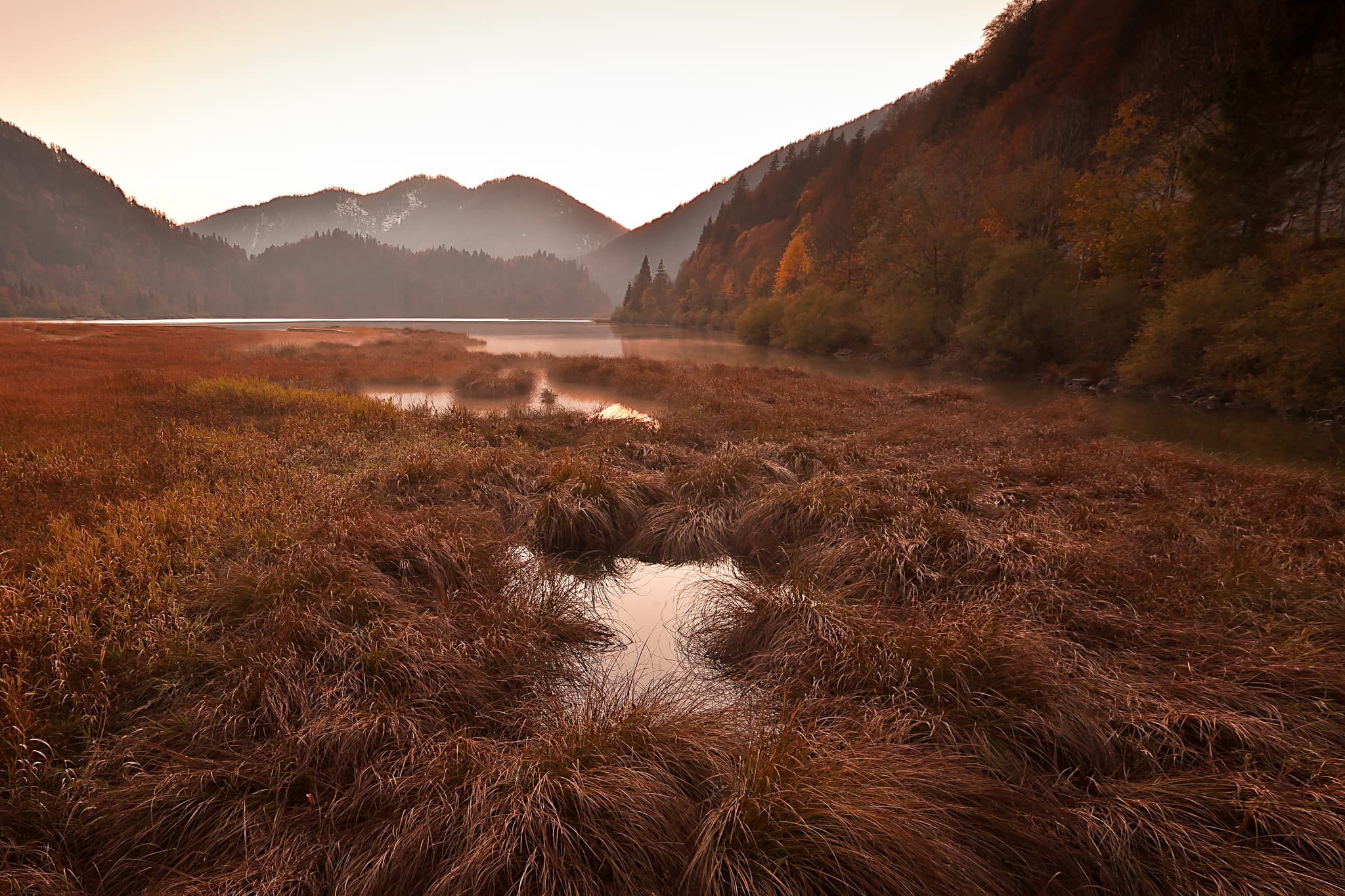 Weitsee im Chiemgau bei Reit im Winkl, Traunstein, Oberbayern, Deutschland. Herbstliche Landschaft mit warmen Farben, Nebel über dem Wasser und Bergen.