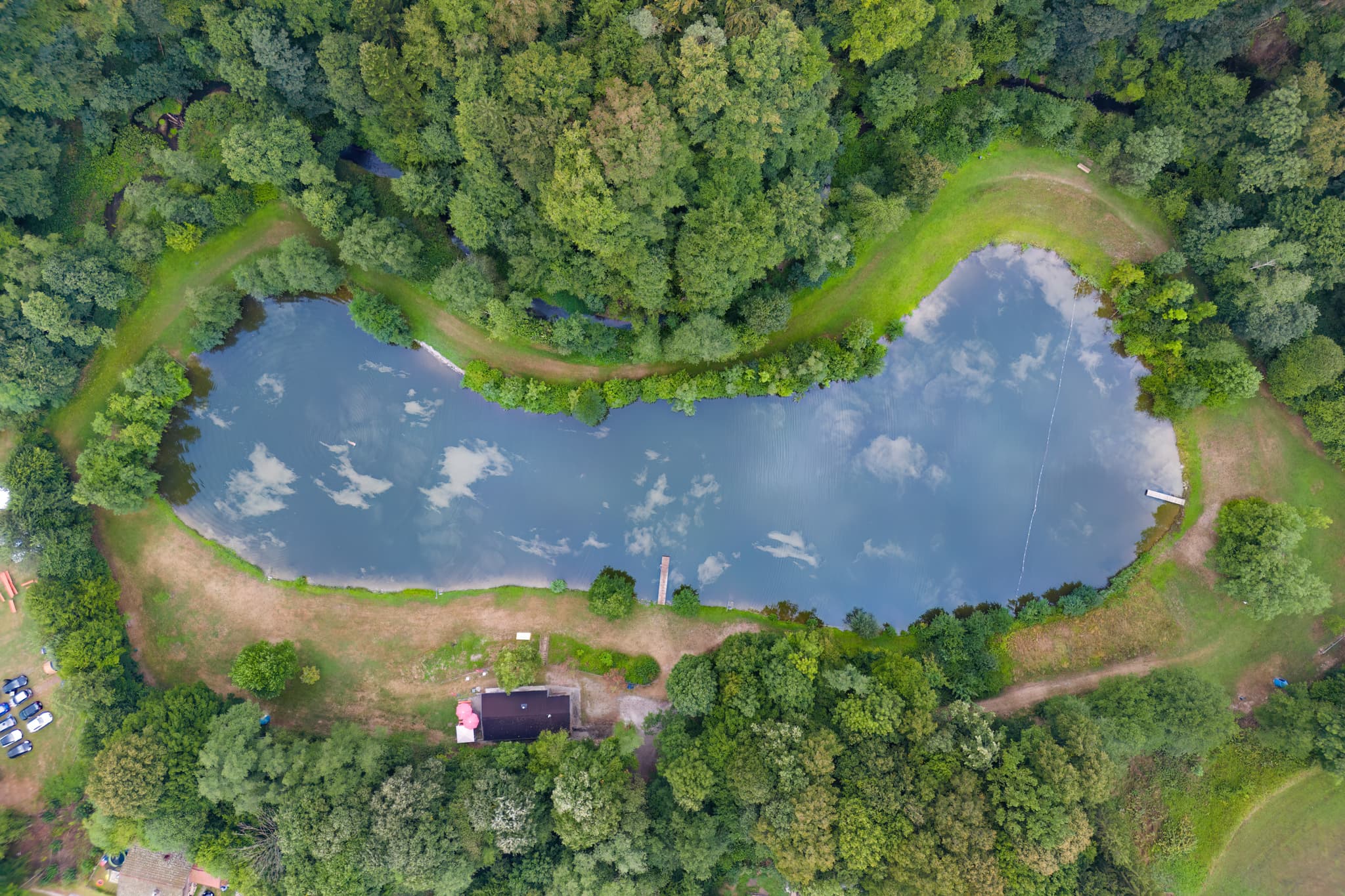 Luftaufnahme des Badesees Hochmühl in Reischach, Altötting, Oberbayern, Deutschland. Der See ist eingebettet in eine grüne Waldlandschaft.8