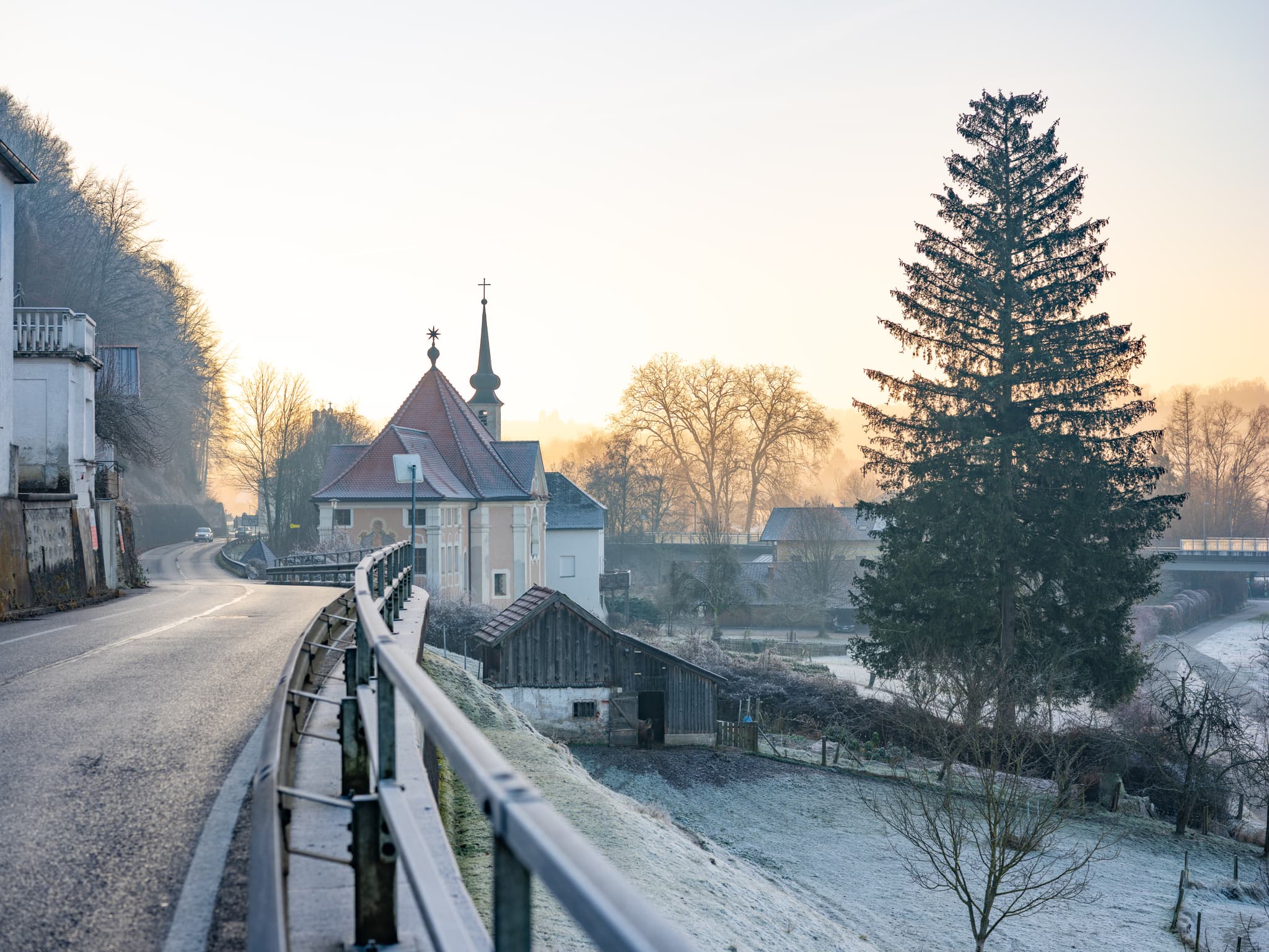 Pfarrkirche Maria Ach in Hochburg-Ach, Braunau am Inn, Oberösterreich, Innviertel, Österreich, eingebettet in eine winterliche Landschaft bei Morgenstimmung.