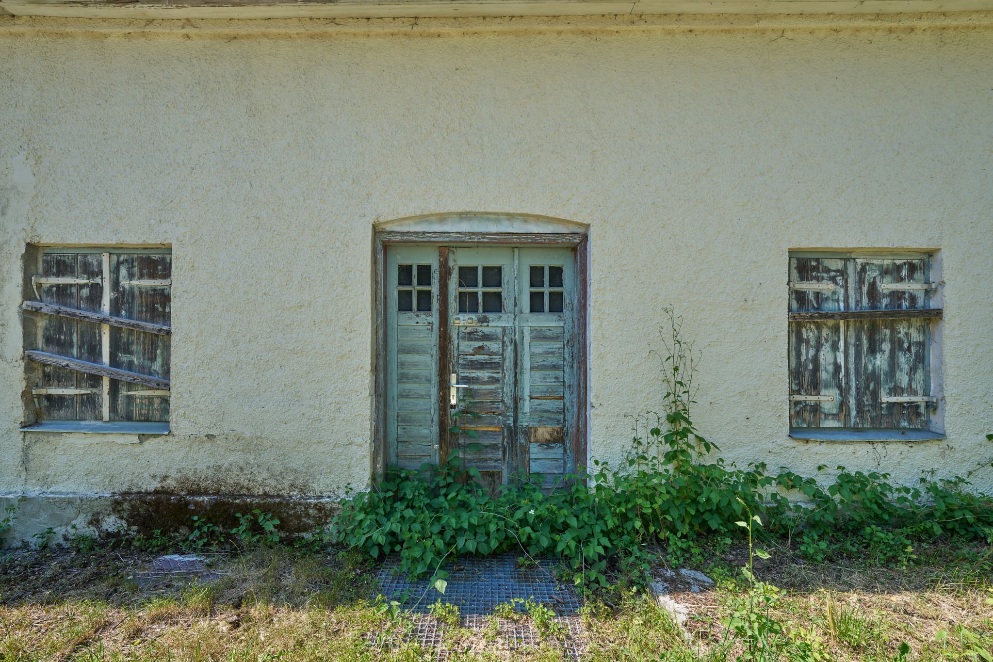 Alte, verwitterte Holztür eines Gebäudes in Ecksberg, Mühldorf am Inn, Oberbayern. Fenster des Bauwerks sind vernagelt.