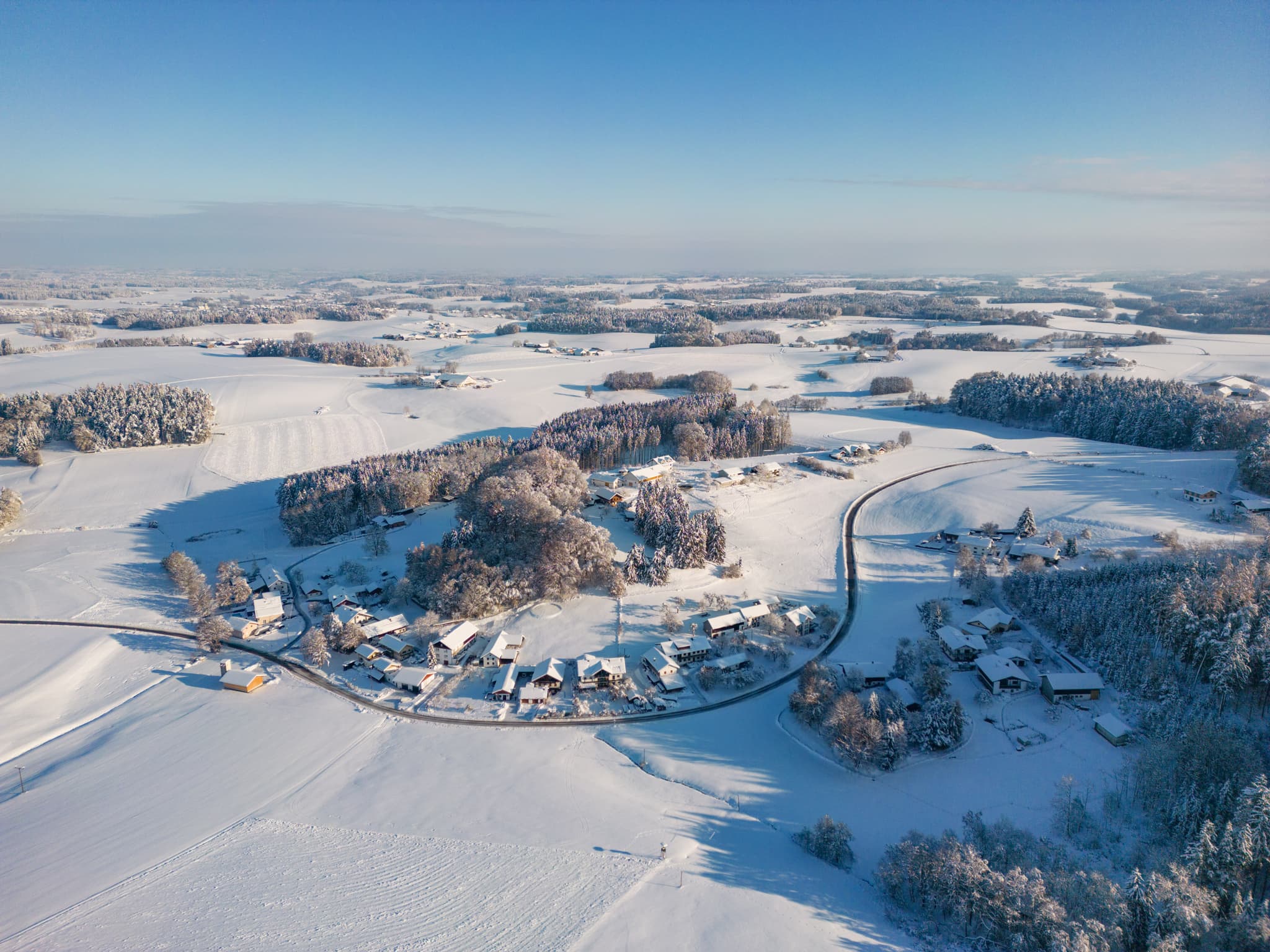 Winterlandschaft Waldberg, Reischach, Landkreis Altötting, Oberbayern. Die verschneite Landschaft mit Häusern, Feldern und Wälder.