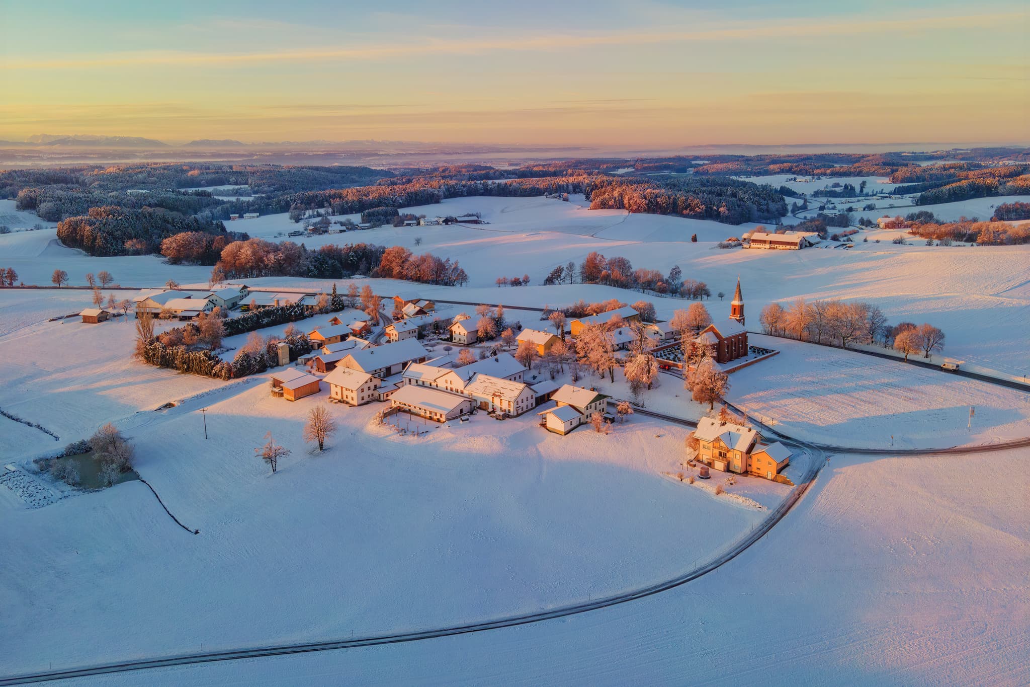 Verschneite Winterlandschaft in Wald bei Winhöring, Pleiskirchen, Altötting, Oberbayern. Häuser und Felder der Region Inn-Salzach, Holzland, Deutschland.
