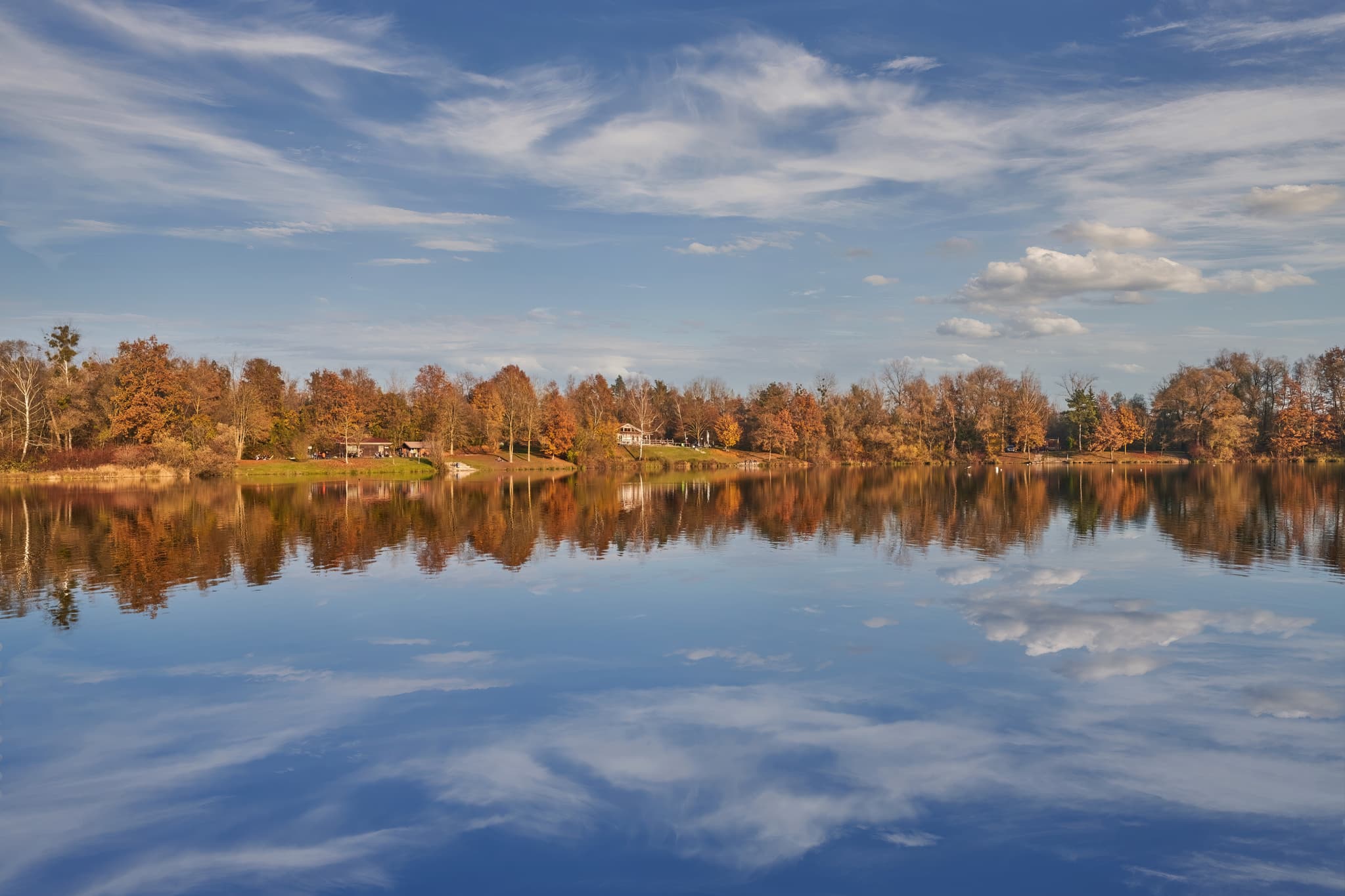 Herbstliche Szene am Waldsee Lago, Kirchdorf am Inn, Rottal-Inn, Niederbayern. Ruhiger See mit buntem Laub an Bäumen und am Ufer.