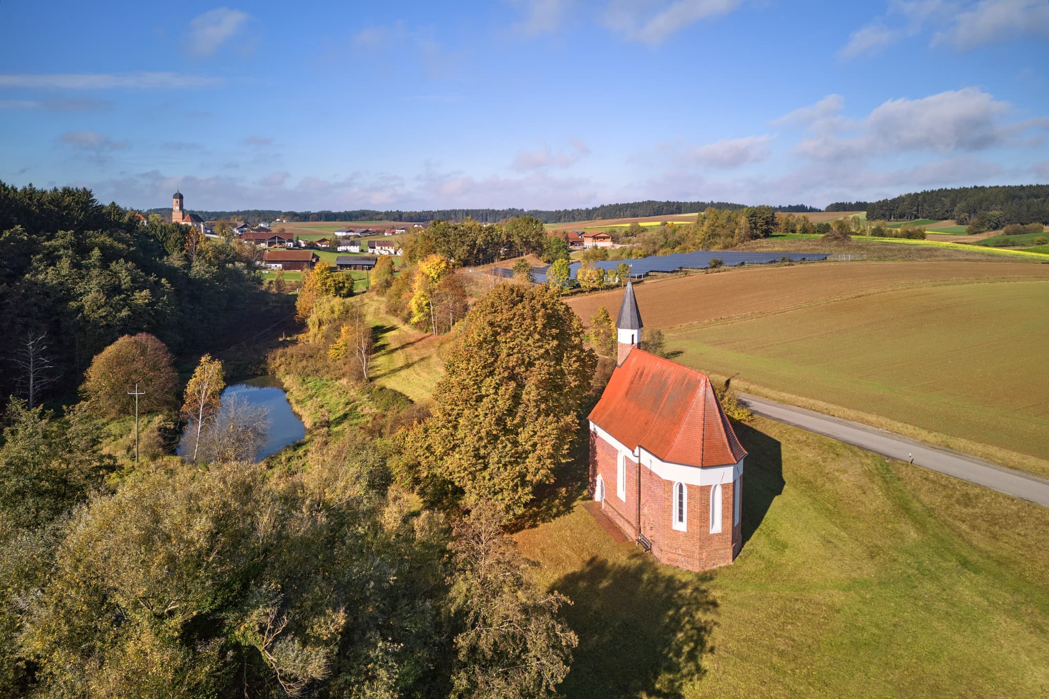 St. Koloman Kirchlein in Martinskirchen, Wurmannsquick, Rottal-Inn, Niederbayern. Ländliche Landschaft im Holzland, Deutschland, mit Teich, Feldern und Wald.