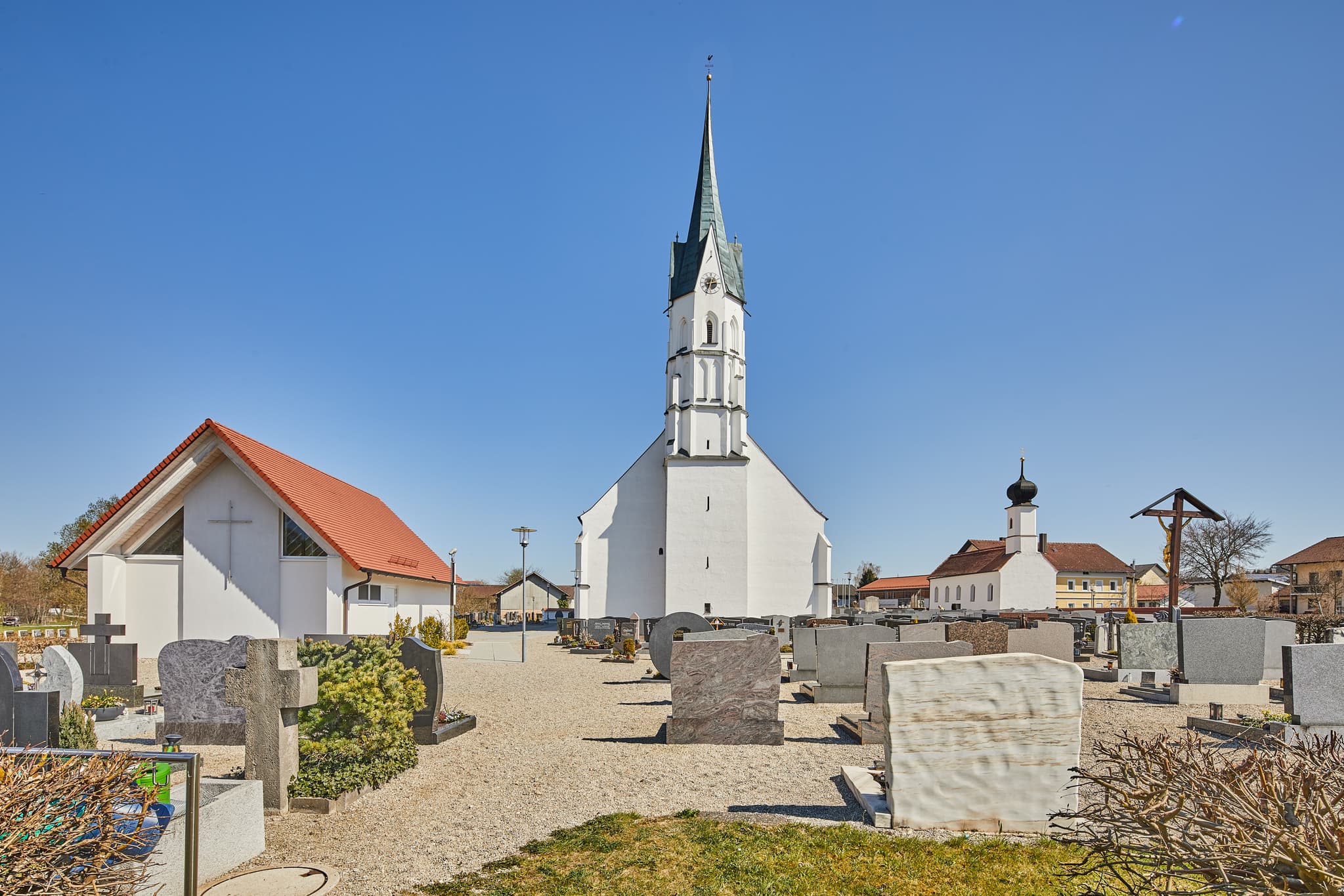 Pfarrkirche Mariä Heimsuchung mit Friedhof in Unterdietfurt, Holzland im Landkreis Rottal-Inn, Niederbayern, Deutschland. Ein ruhiges Motiv unter klarem Himmel.