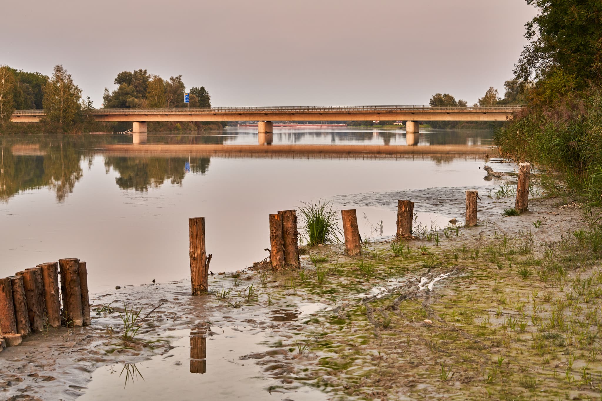 Innbrücke über den Inn nahe Altötting, Landkreis Altötting, Oberbayern, Inn-Salzach, Deutschland. Ansicht der Flusslandschaft mit Uferbereich und Holzpfählen.