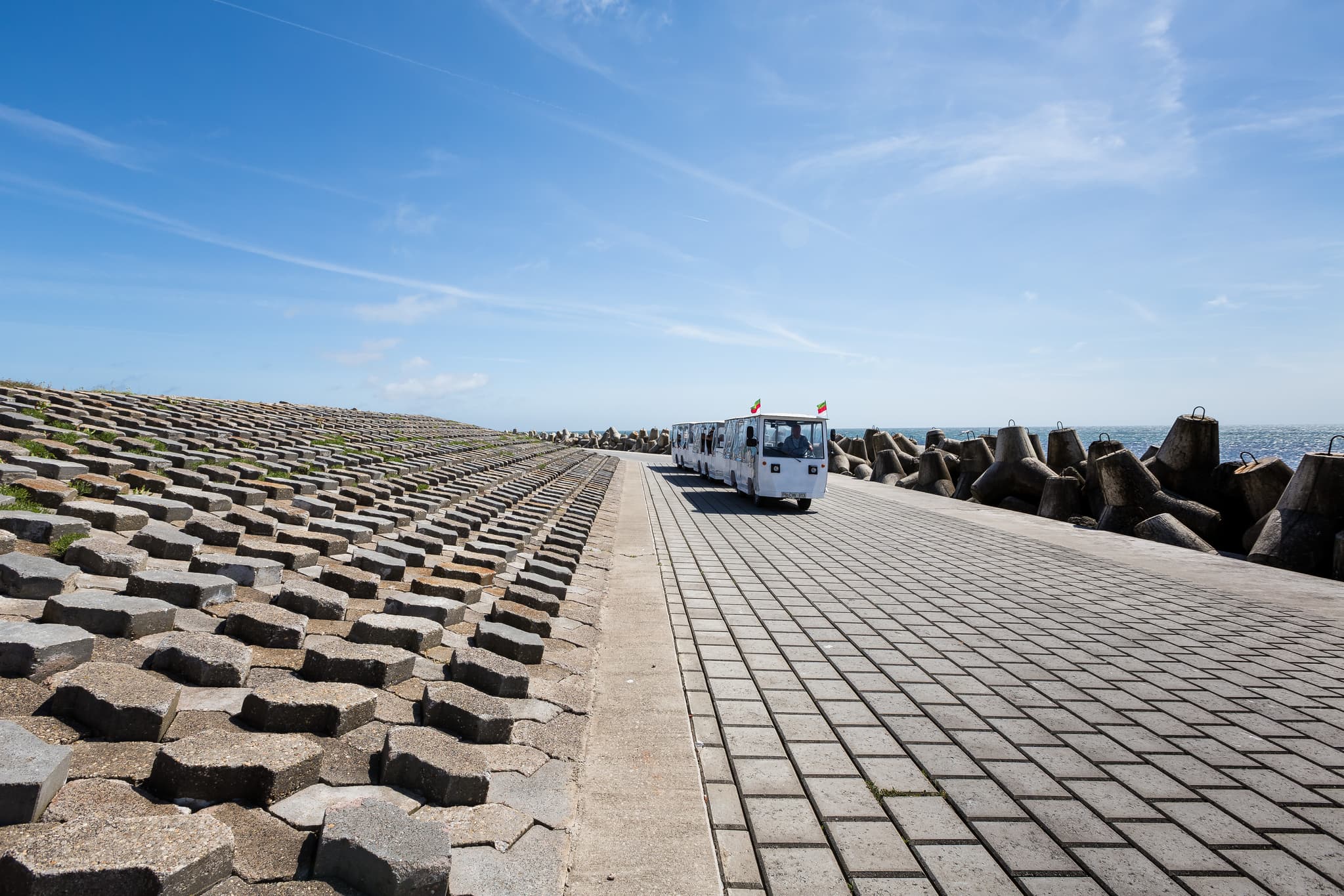 Fahrzeug und Wellenbrecher auf Helgoland, Landkreis Pinneberg, Schleswig-Holstein. Prägnante Küstenlandschaft an der Nordseeküste Deutschlands. Blauer Himmel.