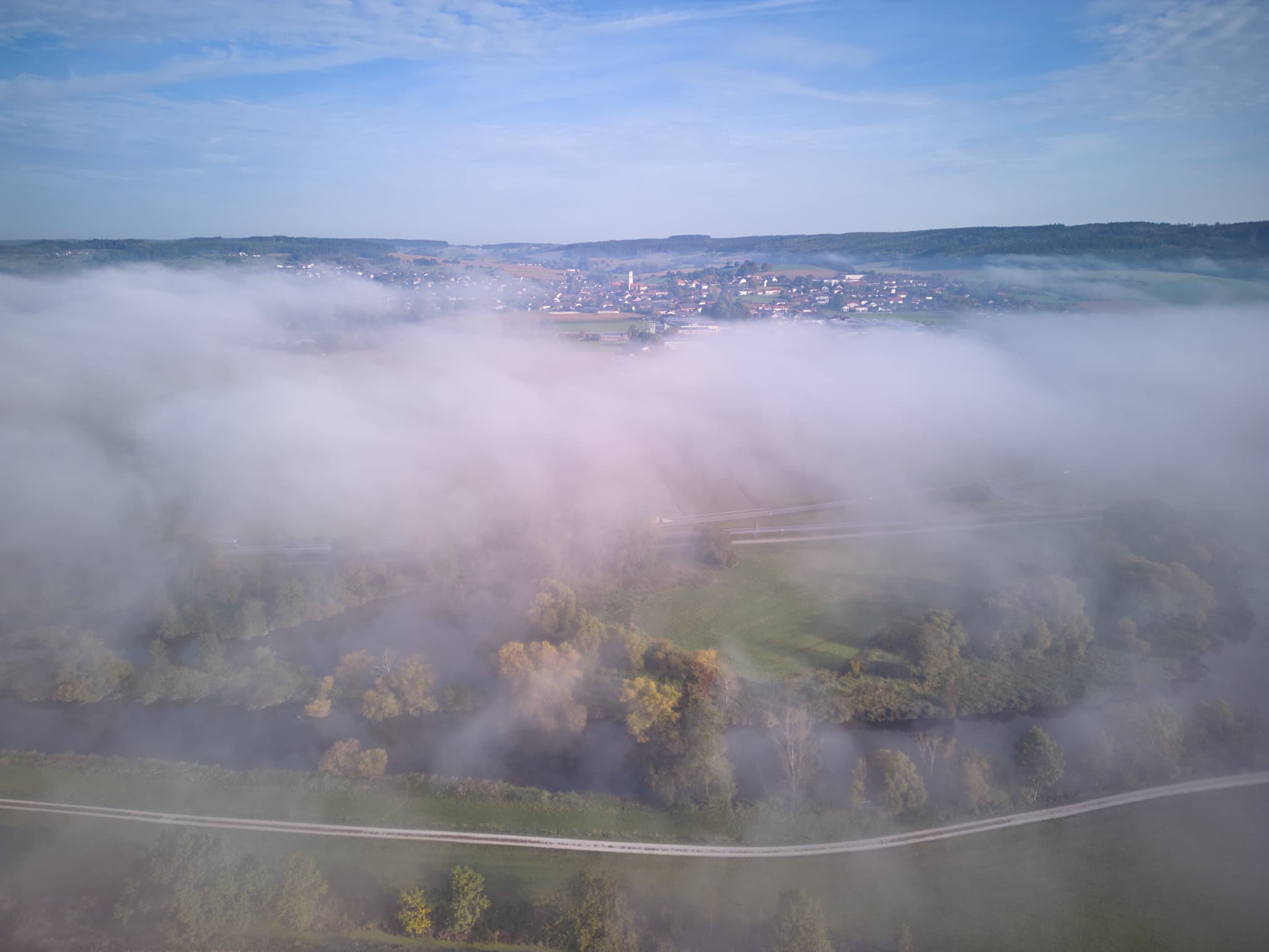 Bad Birnbach, Rottal-Inn, Niederbayern, Deutschland. Herbstlicher Nebel bedeckt Rottal, Felder, Bäume, Straße. Ort im Bäderdreieck ragt teils hervor.