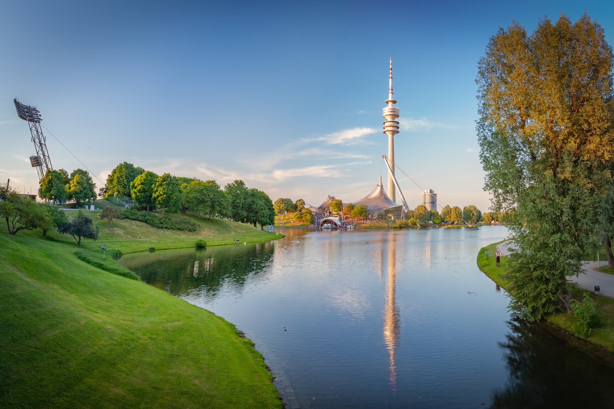 Panoramablick auf Olympiapark 2 mit Olympiasee und Olympiaturm in München, Deutschland. Grüne Ufer, Landkreis München, Oberbayern, Zentralraum München.