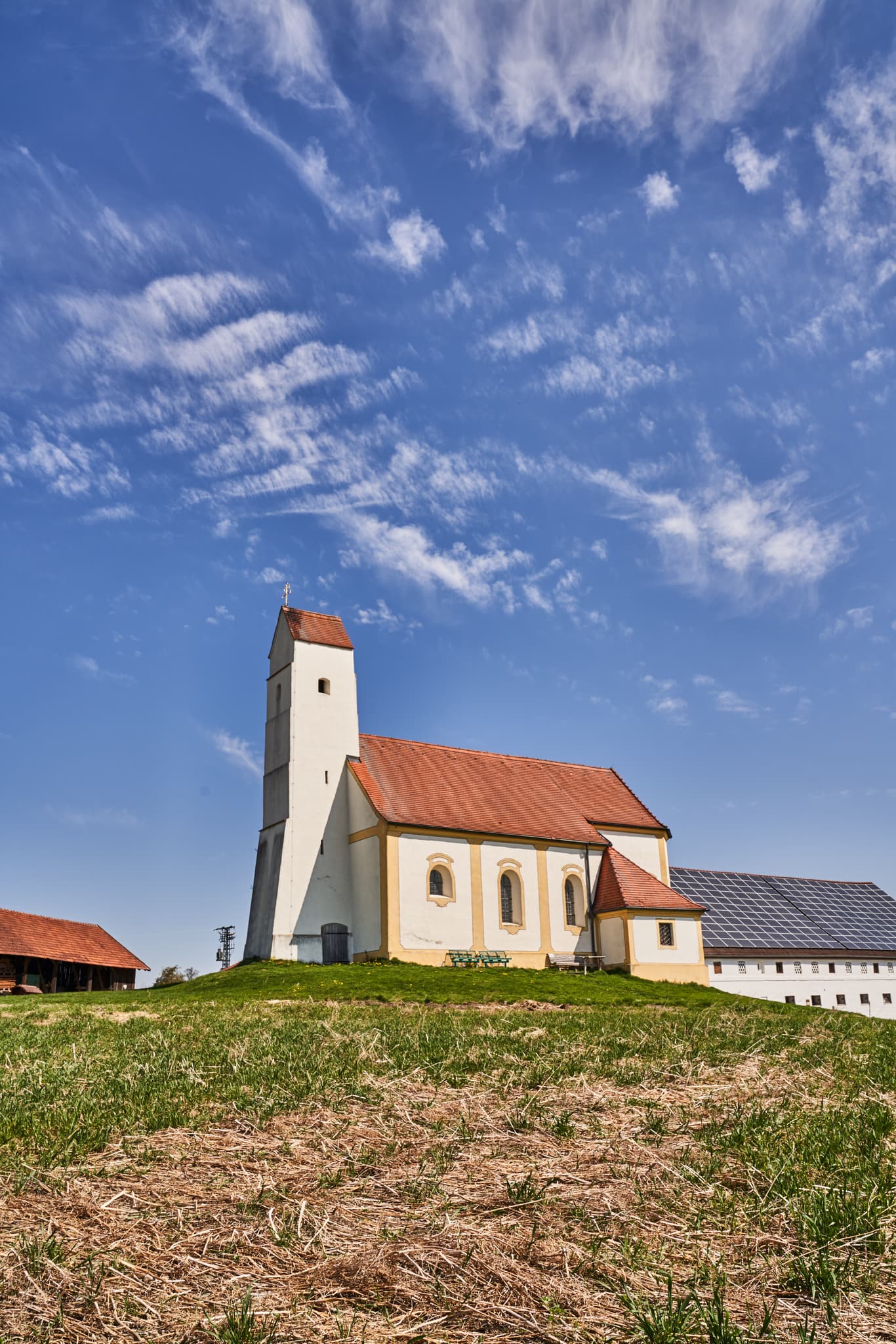 Die Kirchisen Sankt Pankratius in Mettenheim, Landkreis Mühldorf am Inn, Oberbayern, Region Inn-Salzach. Eine historische Kirche unter blauem Himmel.