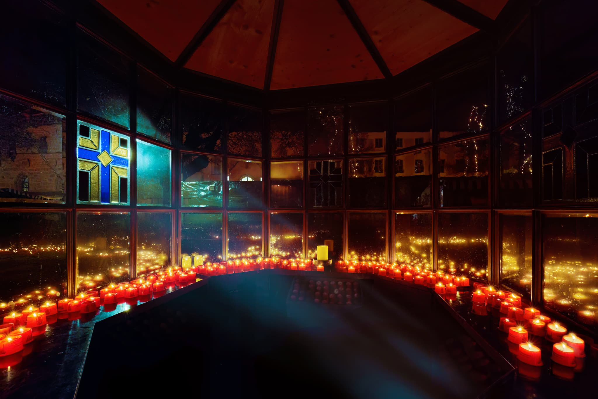 Innenansicht des Lucinariums am Kapellplatz in Altötting, Oberbayern, Deutschland. Kerzen erleuchten den Raum.