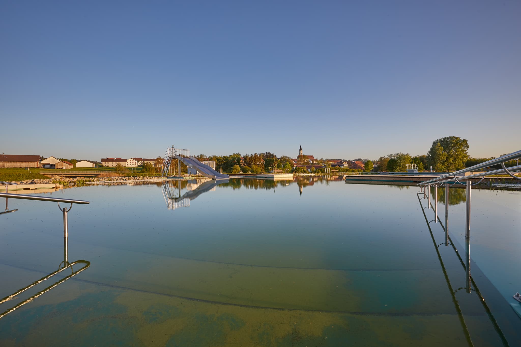 Naturbad am Wassergarten in Mitterskirchen, Niederbayern, Deutschland. Idyllisches Freibad mit Wasserrutsche. Perfekt für einen entspannten Sommertag.