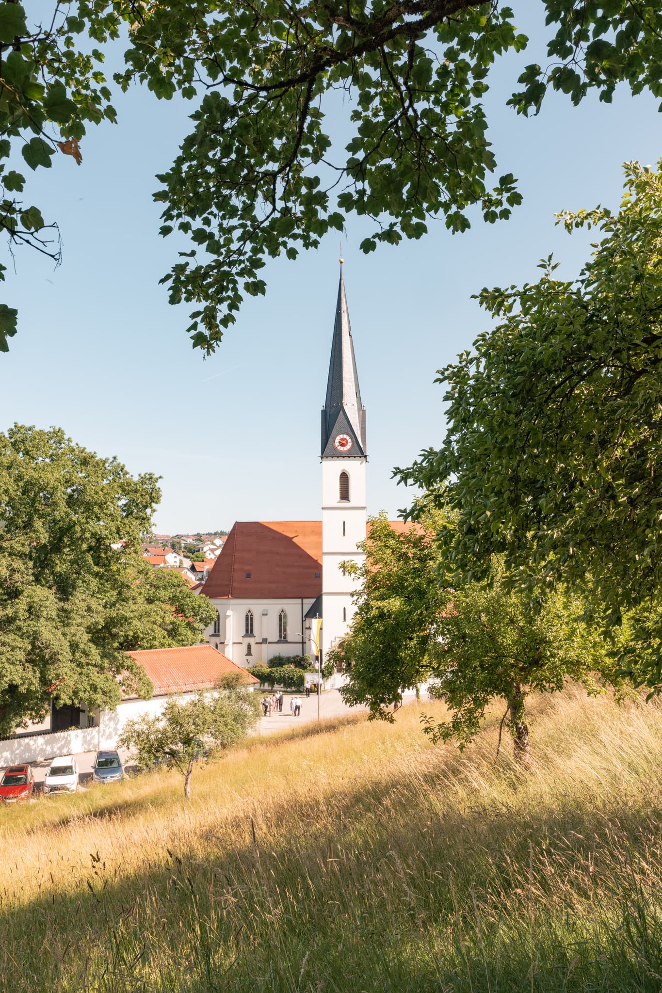 Die Pfarrkirche St. Martin in Reischach, Landkreis Altötting, Oberbayern, Deutschland, vom Pfarrhof-Garten aus fotografiert.