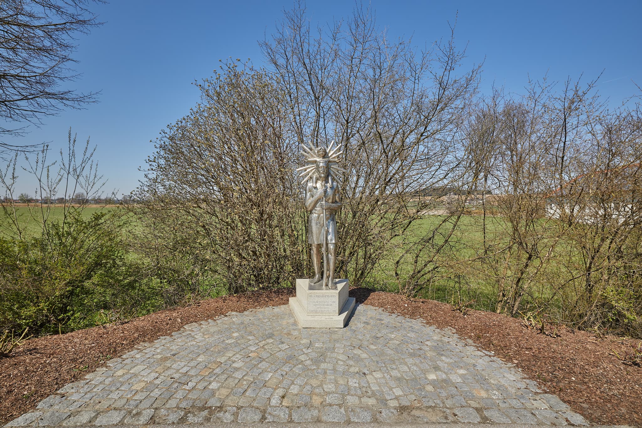 Statue des Heiligen Christopherus in Unterdietfurt, Rottal-Inn, Niederbayern. Die Skulptur befindet sich im Holzland, Deutschland, unter blauem Himmel.
