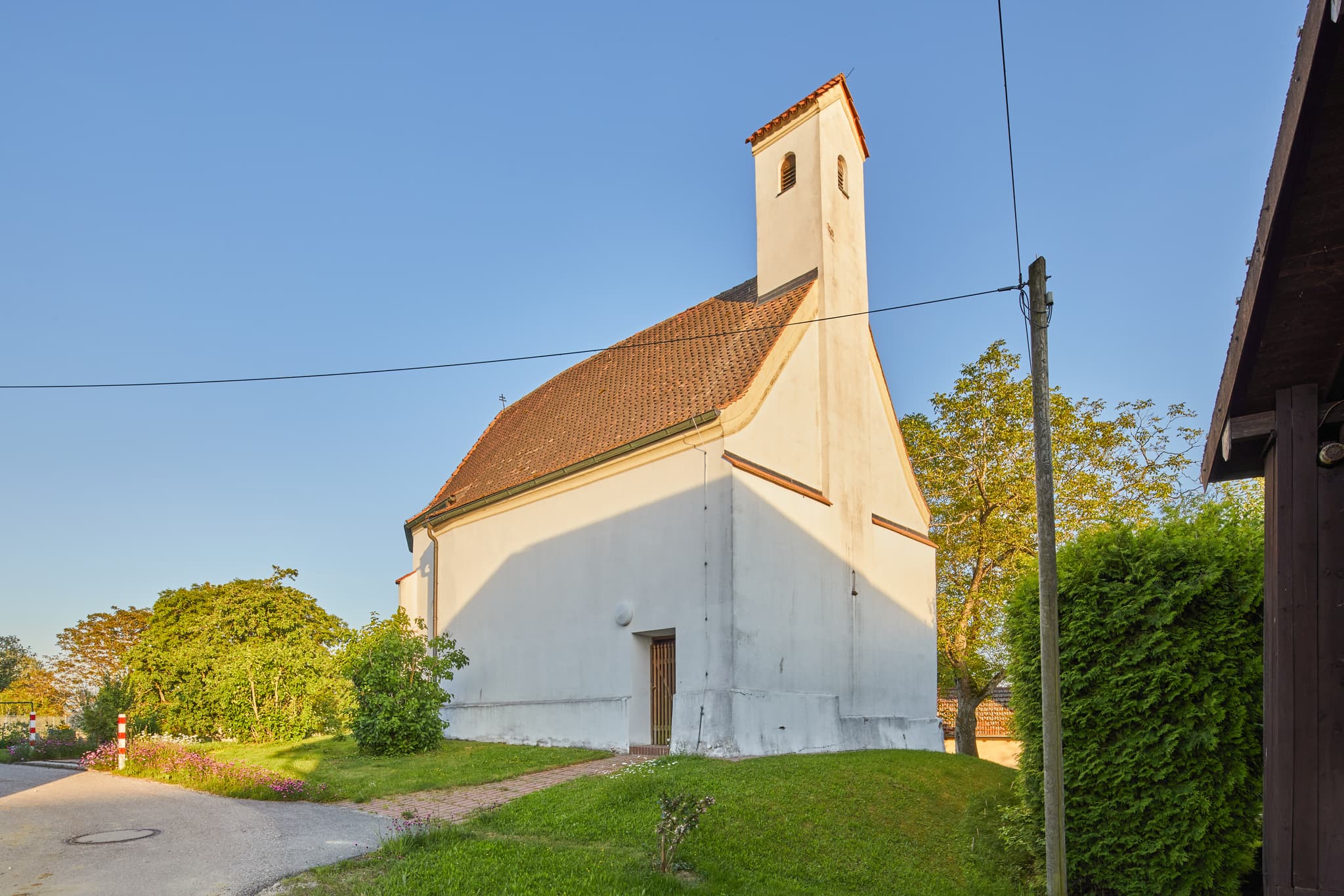 Kirche Sankt Ulrich in Haunertsholzen, Niedertaufkirchen, Mühldorf am Inn, Oberbayern. Weiß verputztes Kirchlein mit Ziegeldach, typische ländliche Szene.