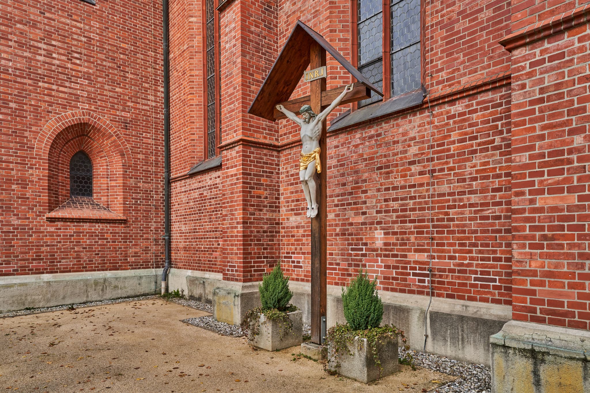 Kruzifix an der Ziegelwand der Kirche St. Stephanus Hörniweg in Schönau, Rottal-Inn, Niederbayern, Deutschland. Motiv aus der Region Holzland.