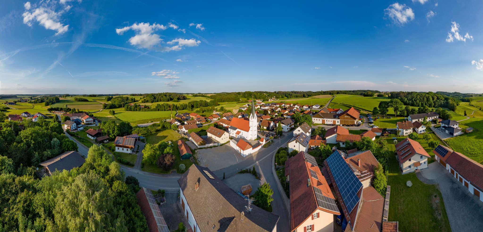 Ortsansicht von Arbing mit der Pfarrkirche St. Georg. Eingebettet in die grüne Landschaft der Region Inn-Salzach, Landkreis Altötting, Oberbayern, Deutschland.