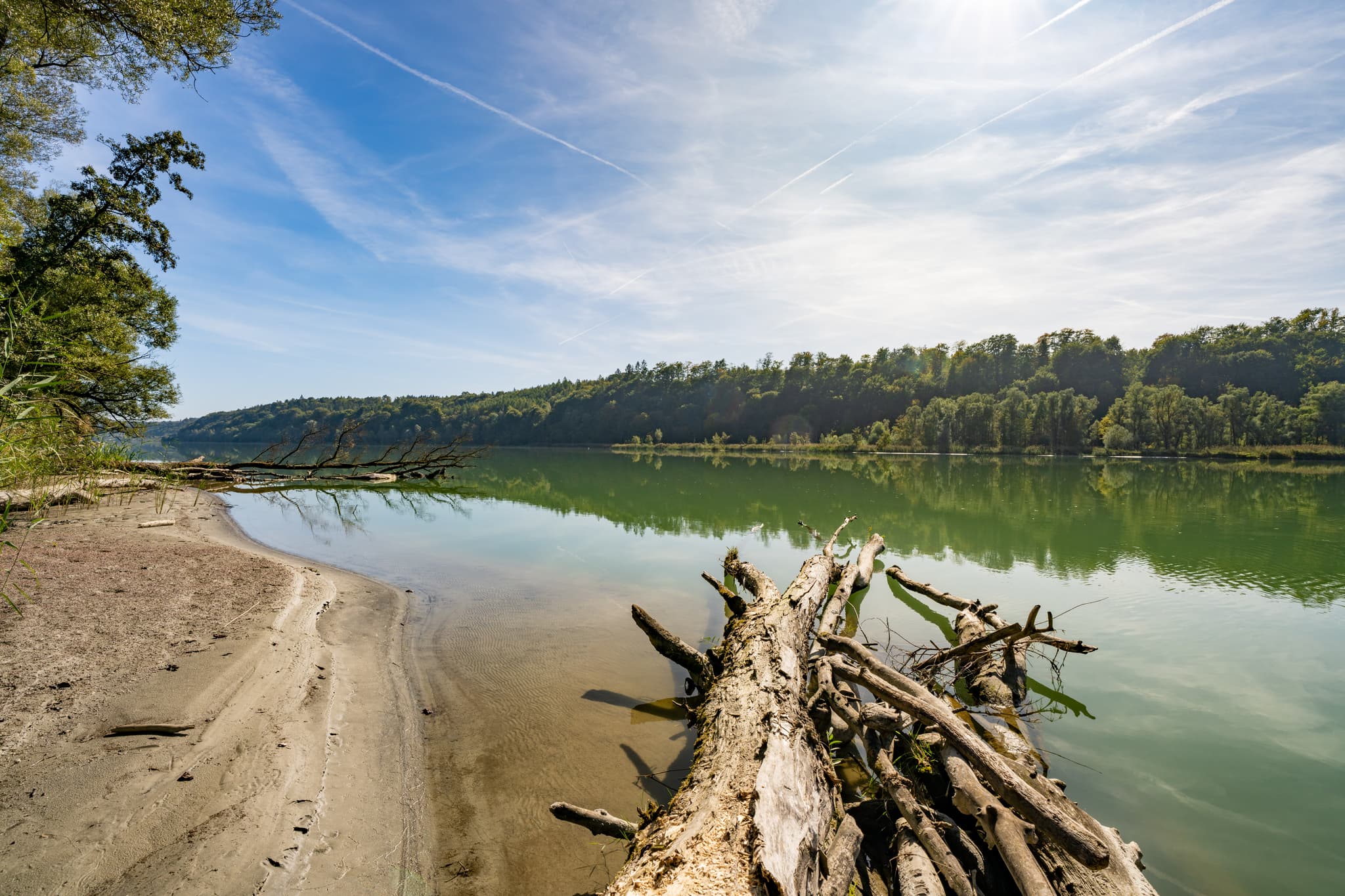 Salzach vor Innspitz, Haiming, Landkreis Altötting, Oberbayern, Region Inn-Salzach, Deutschland. Ruhiges Gewässer mit Ufer und Treibholz unter blauem Himmel.