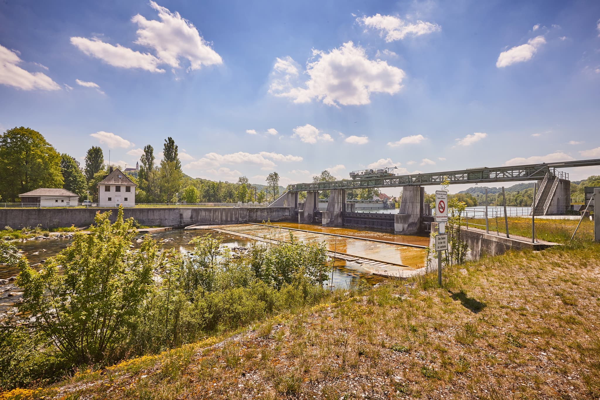 Stauwehr am Fluss in Burgkirchen-Hirten, Burgkirchen, Altötting, Oberbayern. Grüne Landschaft der Inn-Salzach Region in Deutschland unter blauem Himmel.