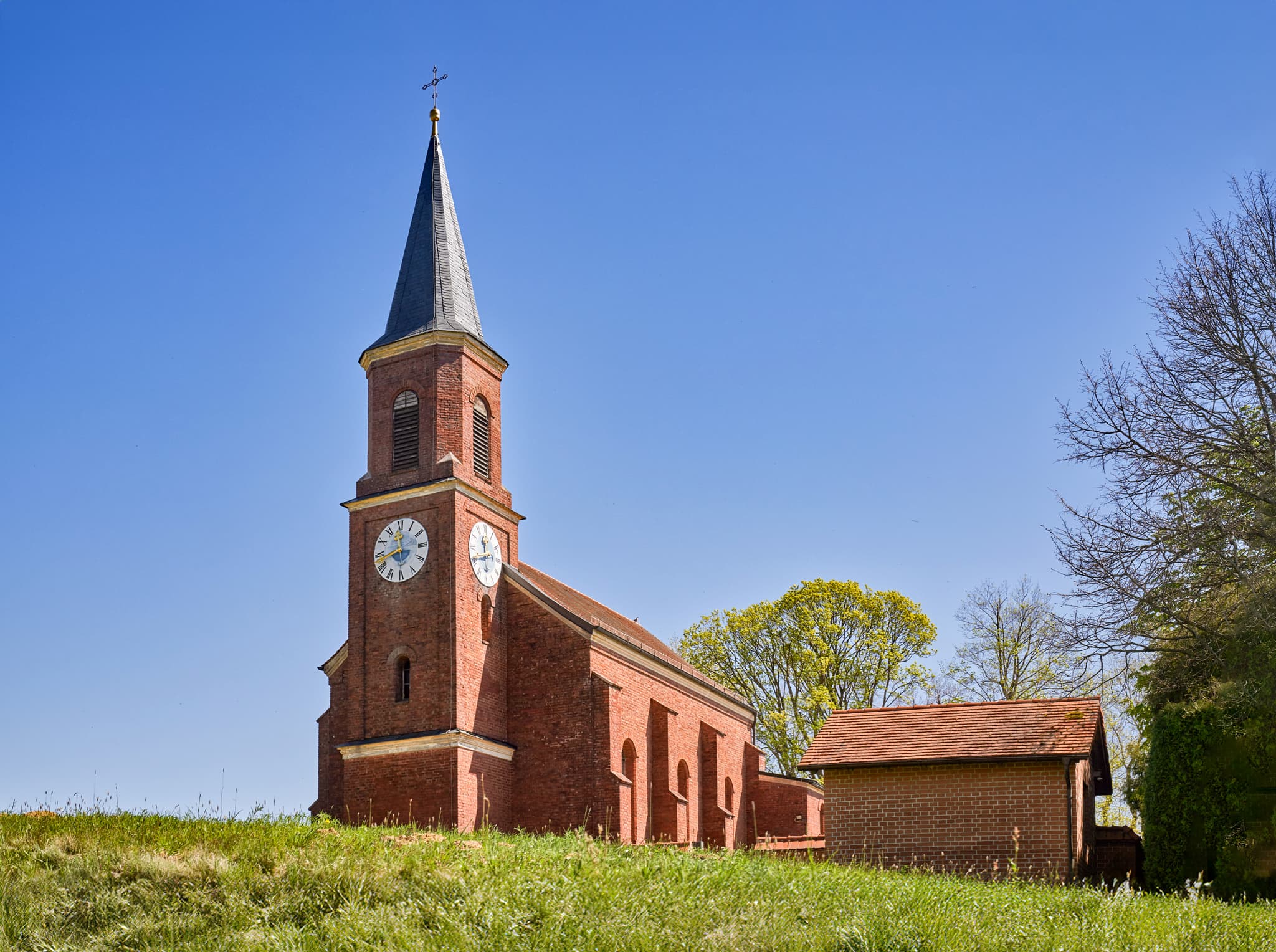 Kirche auf grasbewachsenem Hügel, aufgenommen in Wald bei Winhöring, Gemeinde Pleiskirchen, Landkreis Altötting, Oberbayern, Region Inn-Salzach, Deutschland.