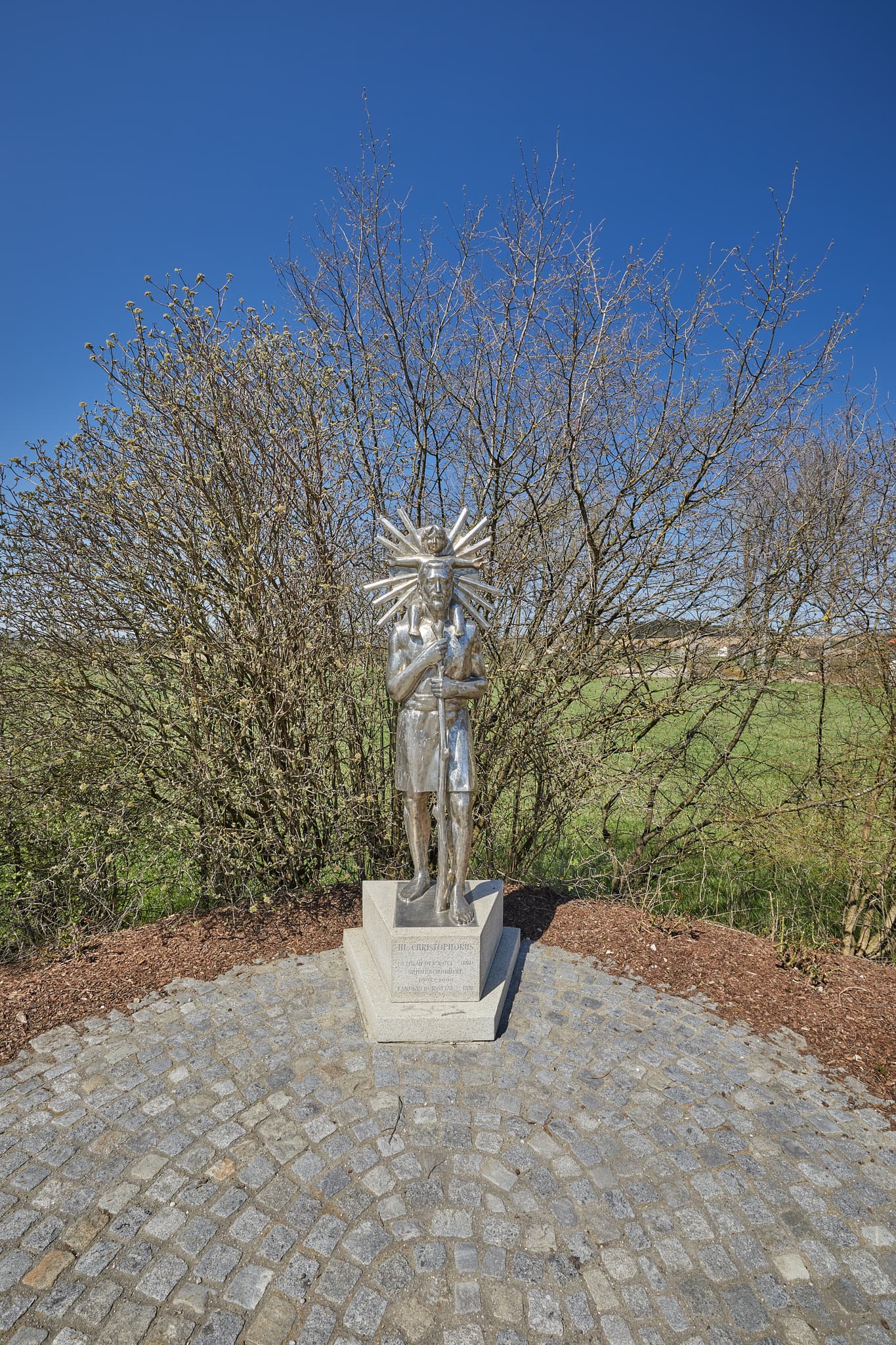 Statue des Heiligen Christopherus in Unterdietfurt, Rottal-Inn, Niederbayern. Die Skulptur befindet sich im Holzland, Deutschland, unter blauem Himmel.
