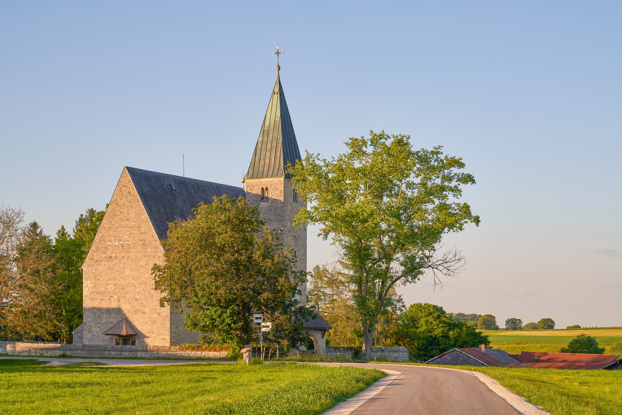 Die Kirche St. Pankratius in Meggenthal, Ortsteil von Tittmoning, Landkreis Traunstein, Oberbayern, Deutschland im Chiemgau, umgeben von Feldern und Straße.
