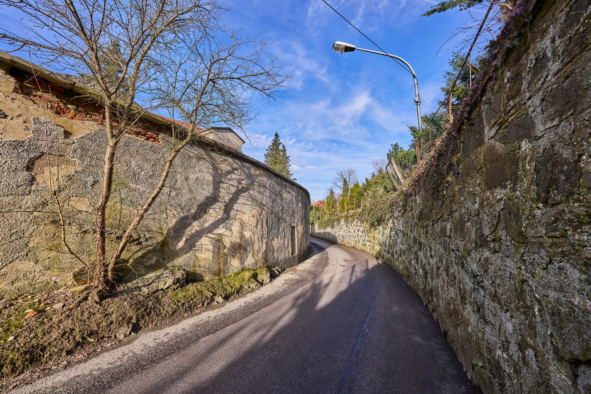 Bild zeigt eine Straße am Friedhof in Innstadt, Landkreis Passau, Niederbayern, Inn-Salzach Region, Deutschland. Historische Steinmauern säumen den Weg.